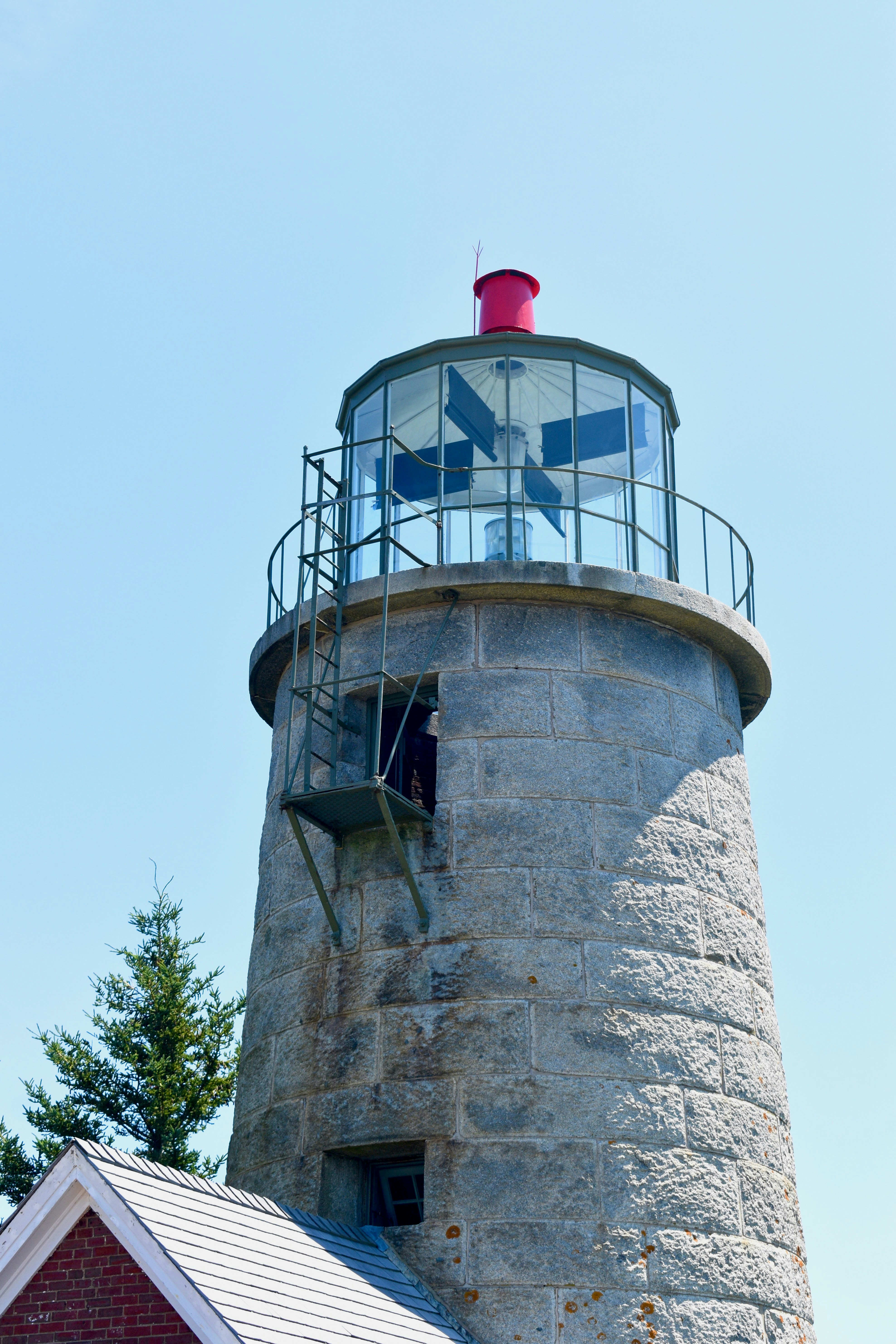 Historic stone lighthouse with a red cap under clear sky