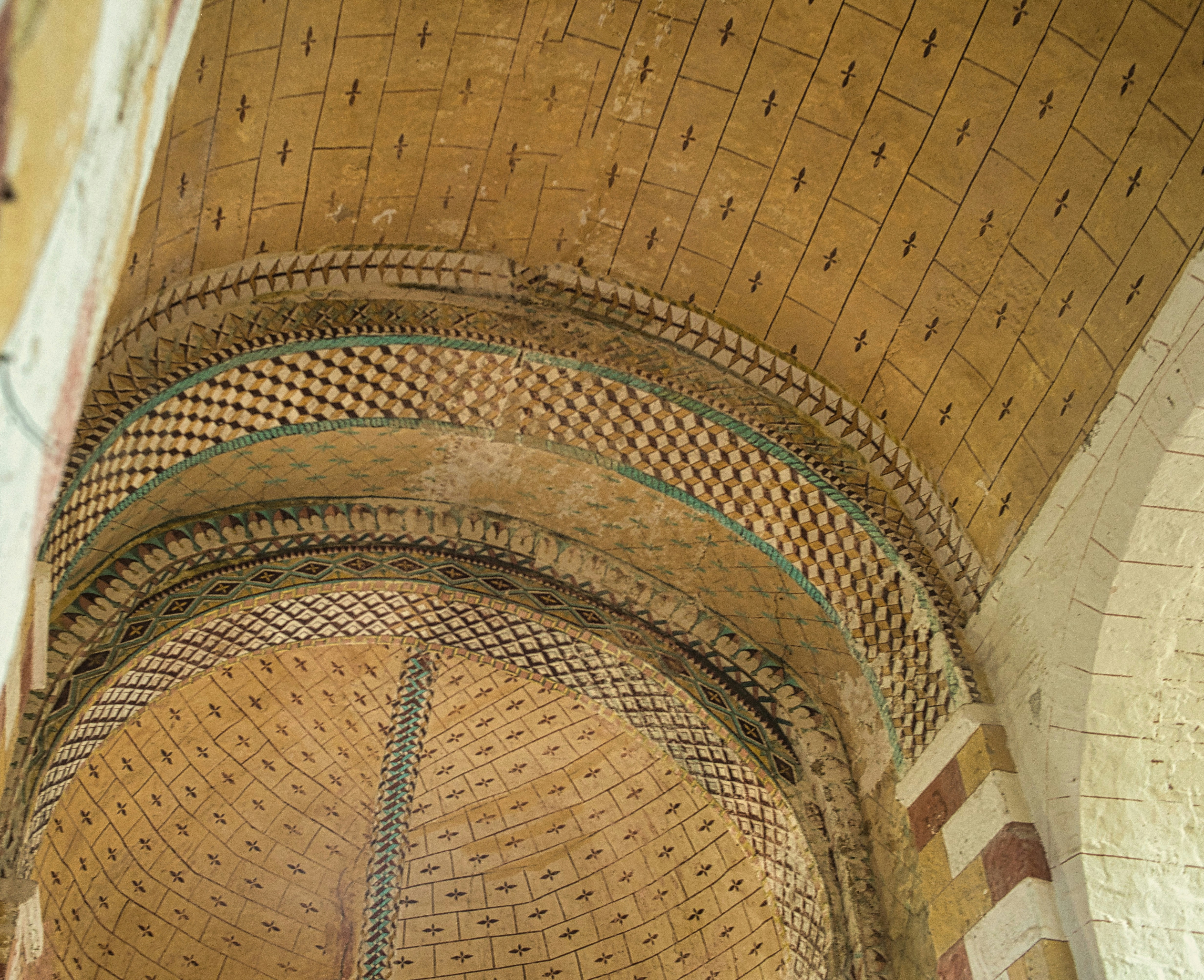 Intricate patterns adorn an arched, ancient ceiling.
