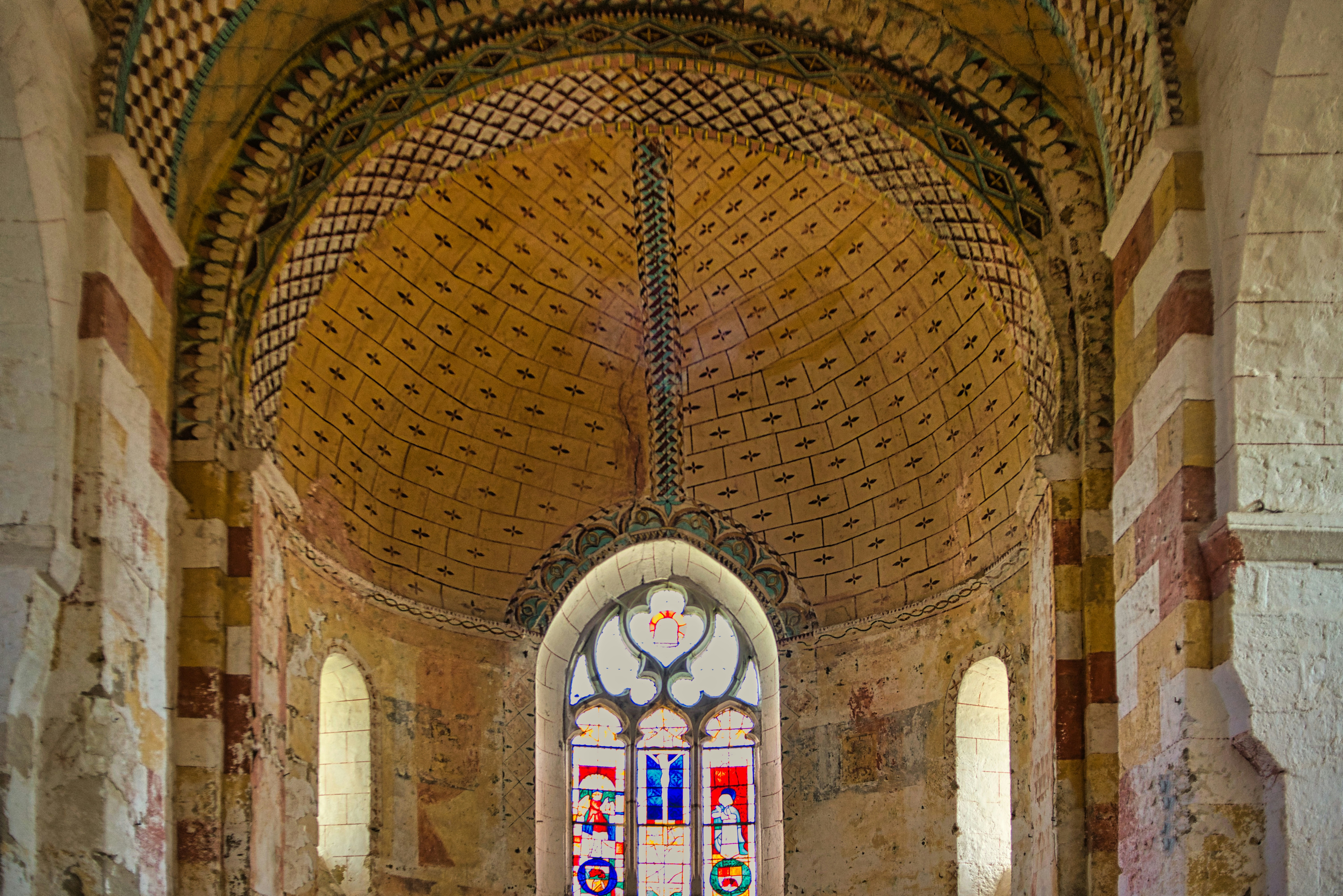 Ancient church interior with ornate domed ceiling and stained glass.