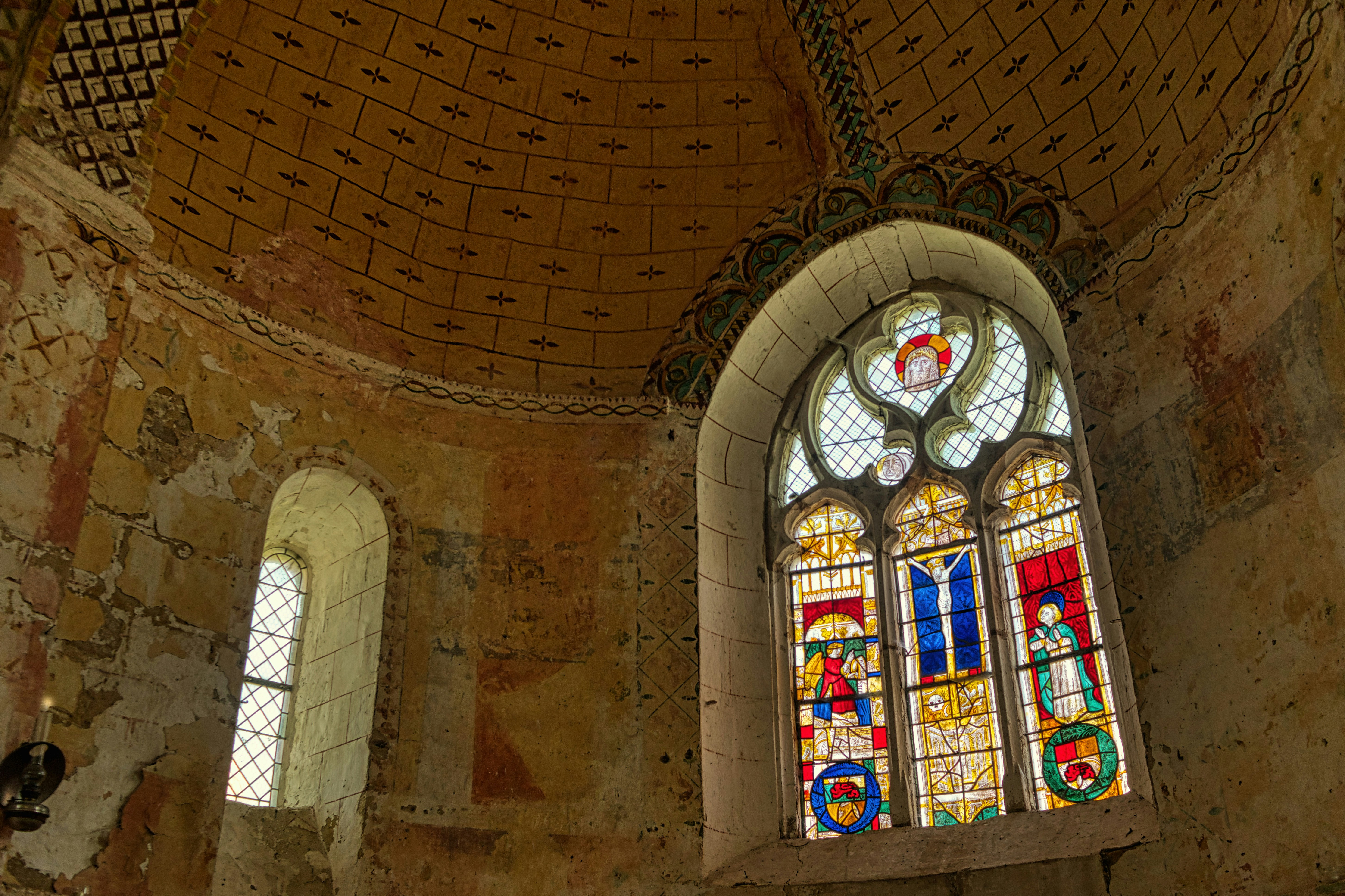 Old church interior with stained glass windows and painted ceiling.