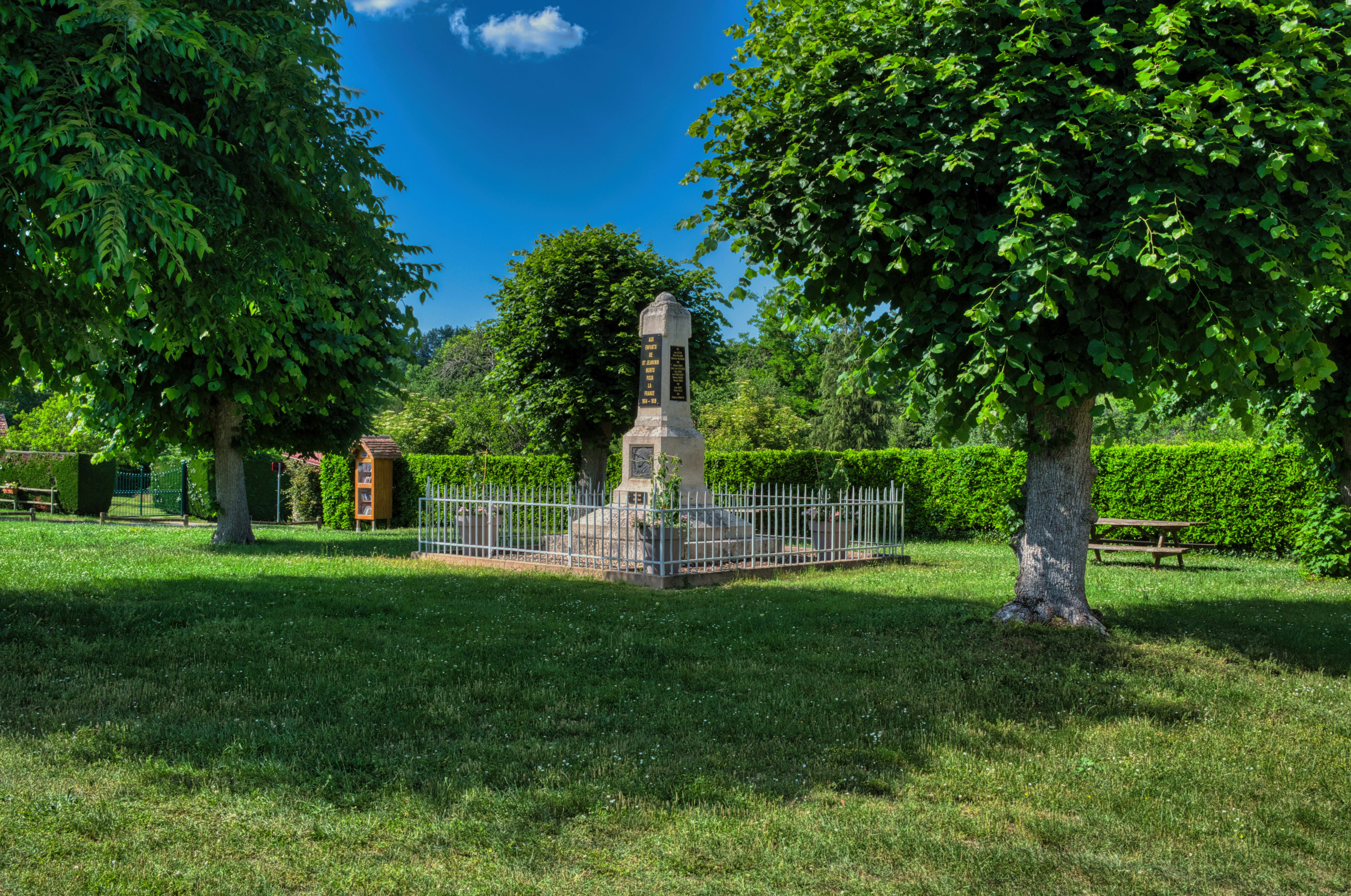 An old stone memorial stands in a sunny, green park.