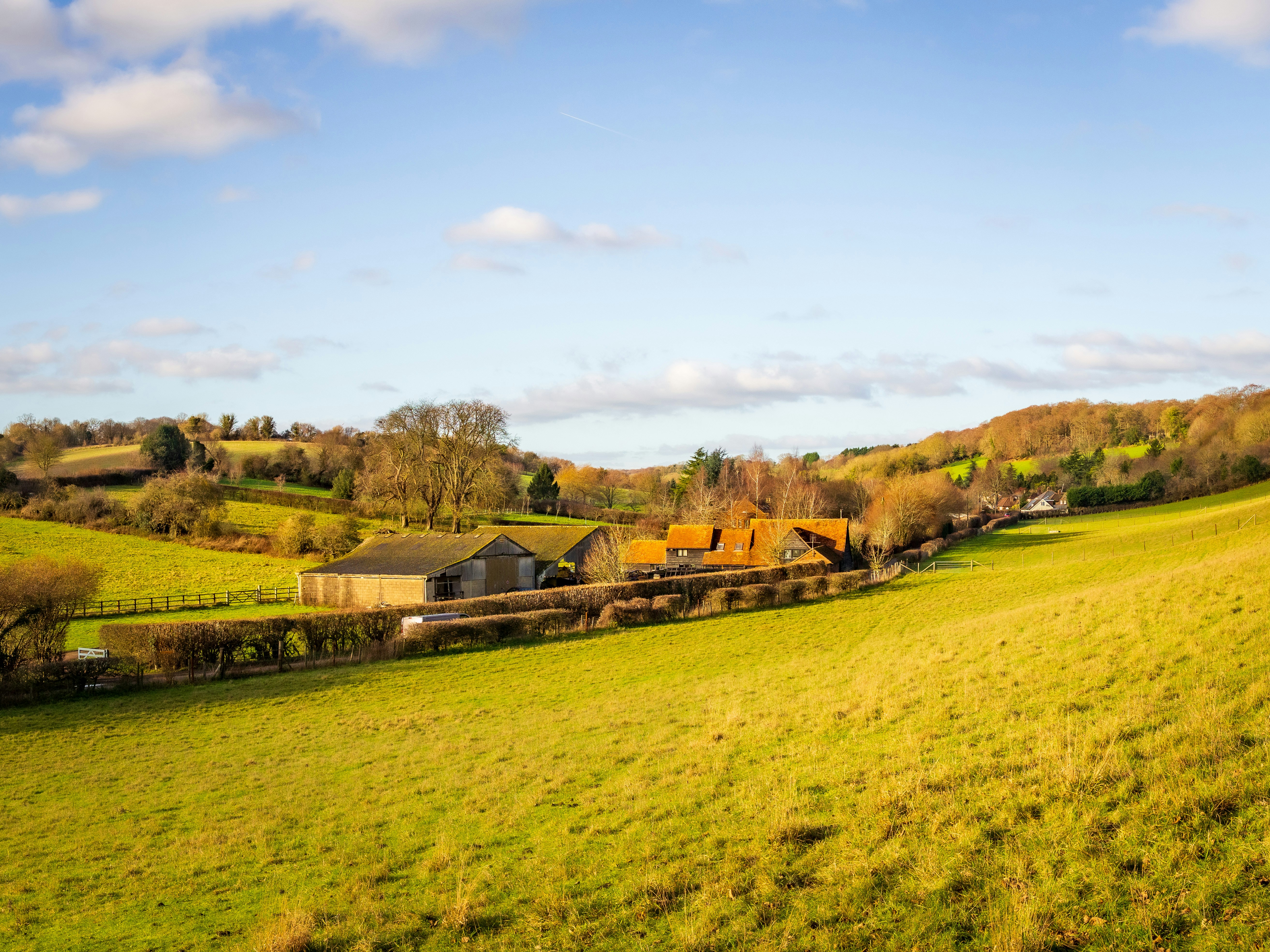 Farm buildings nestled in green rolling hills.
