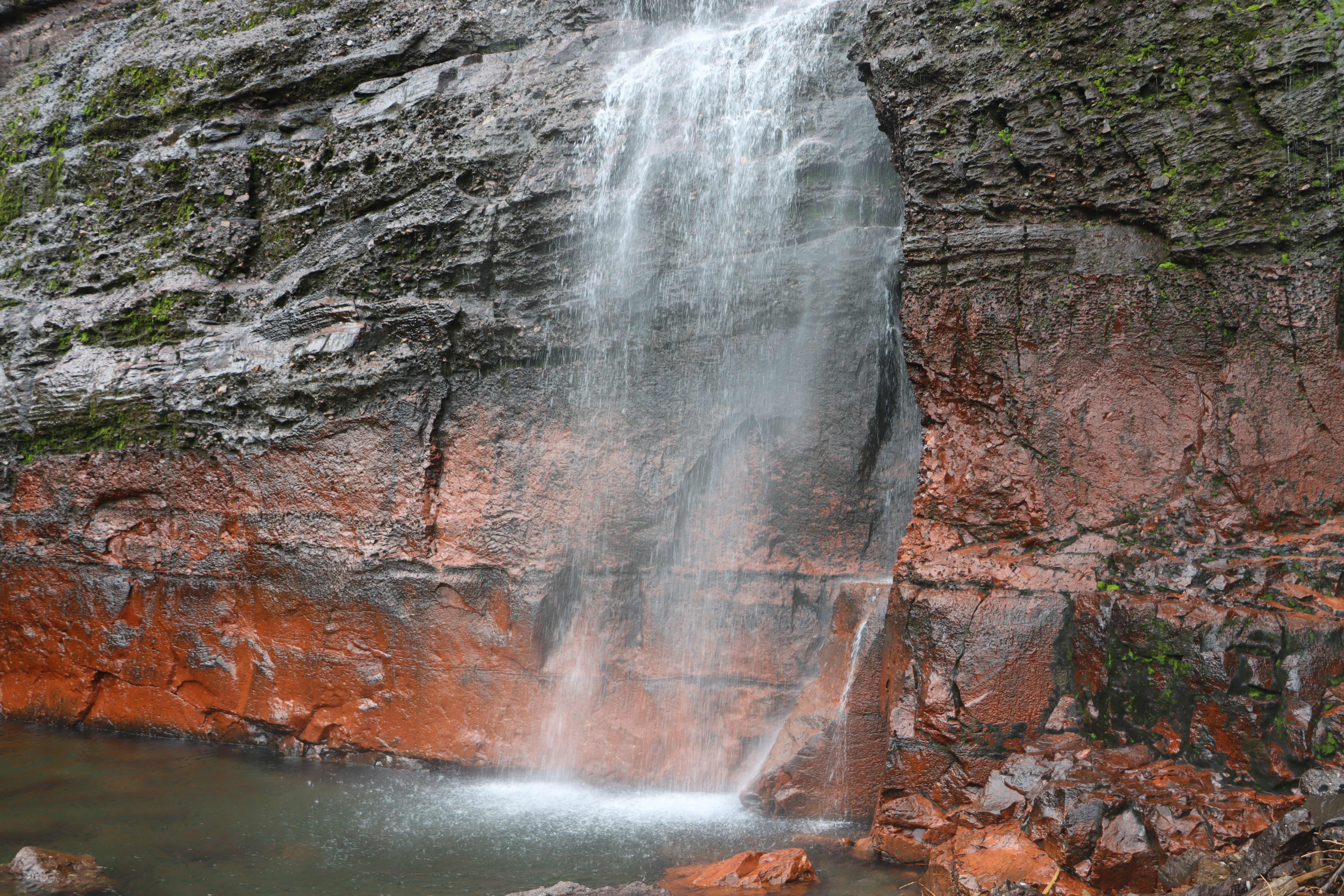Waterfall flowing over red and gray rocky cliffs