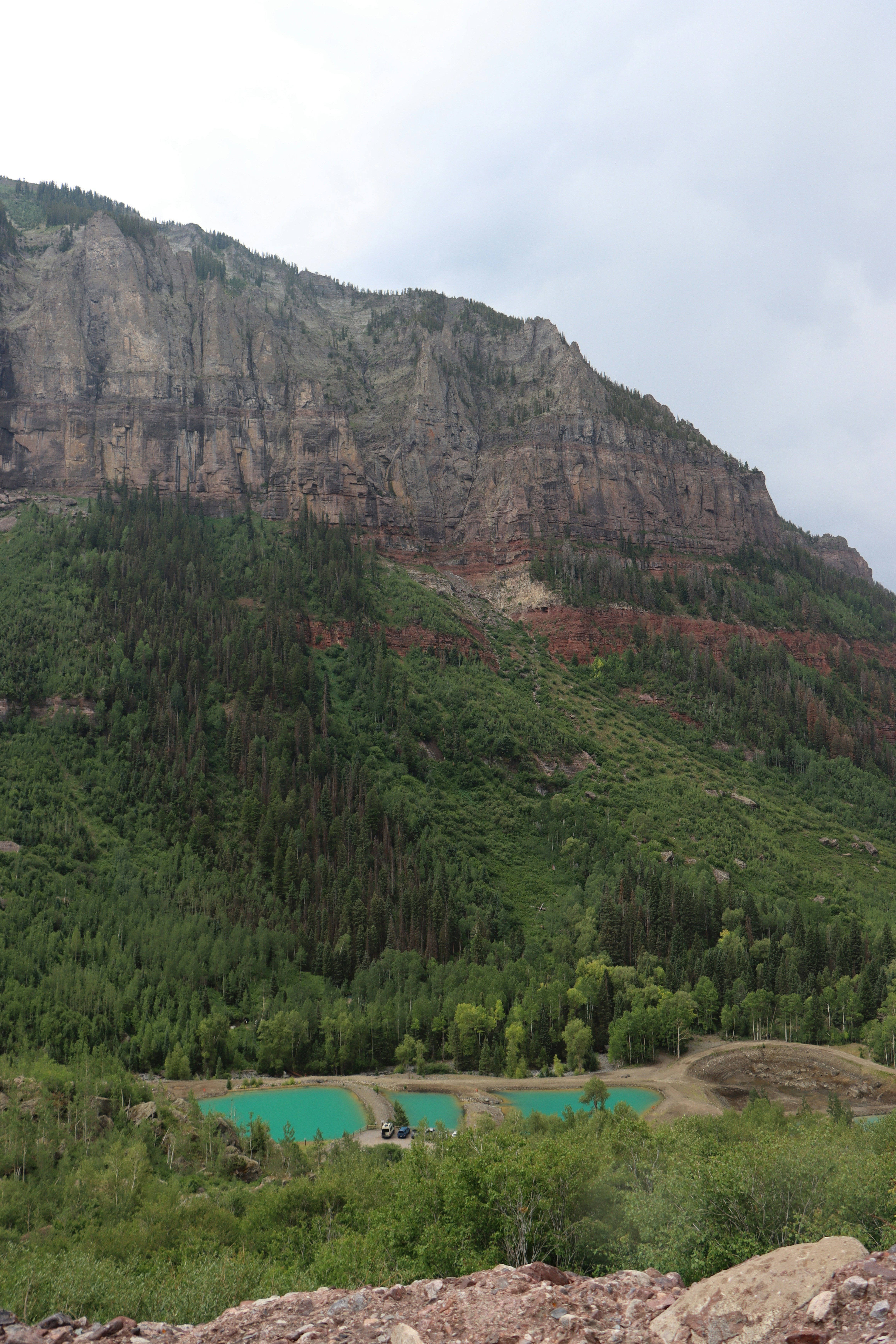 A large mountain overlooks turquoise ponds and green forests