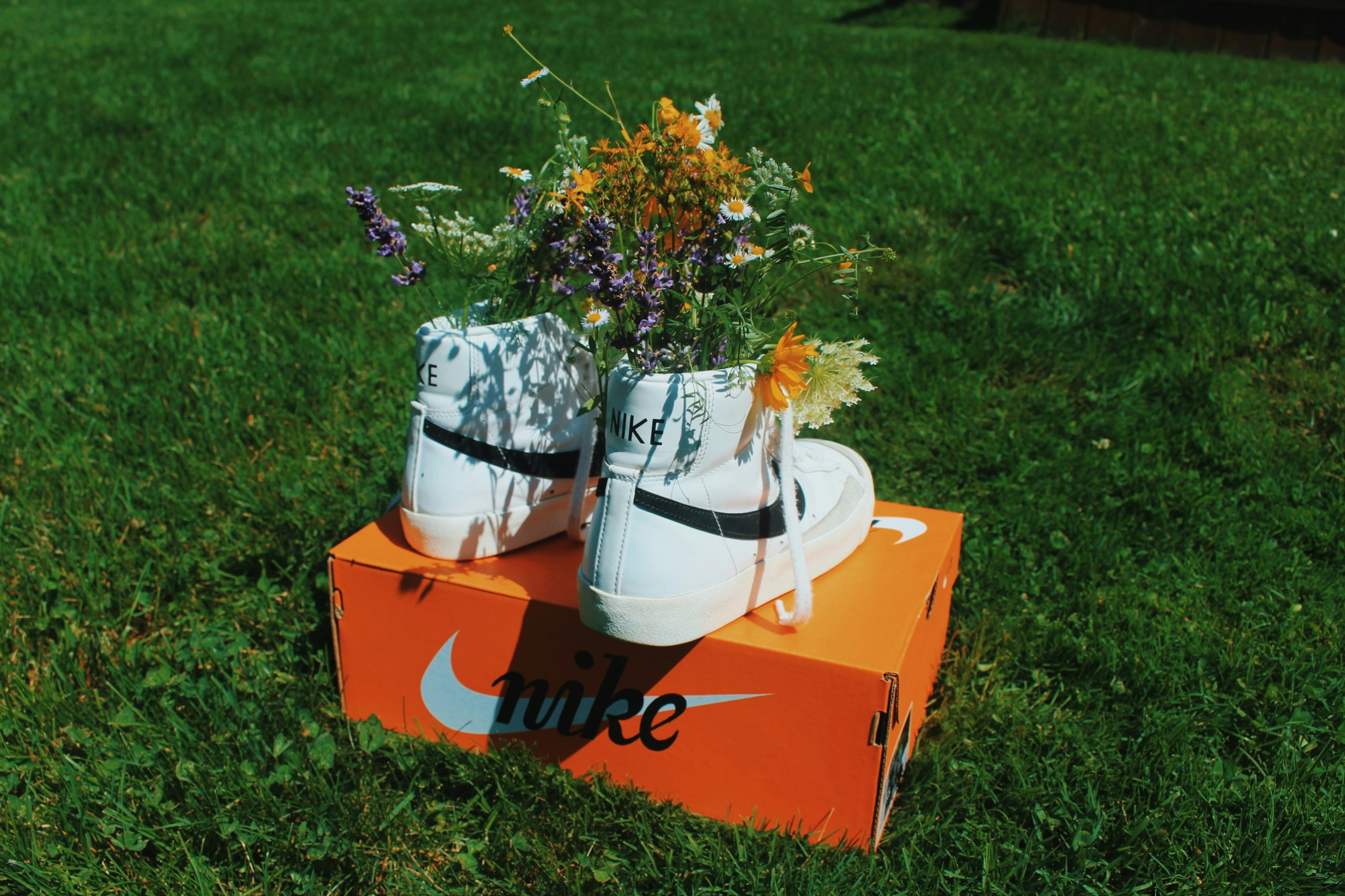 Sneakers with flowers on a nike box in green grass