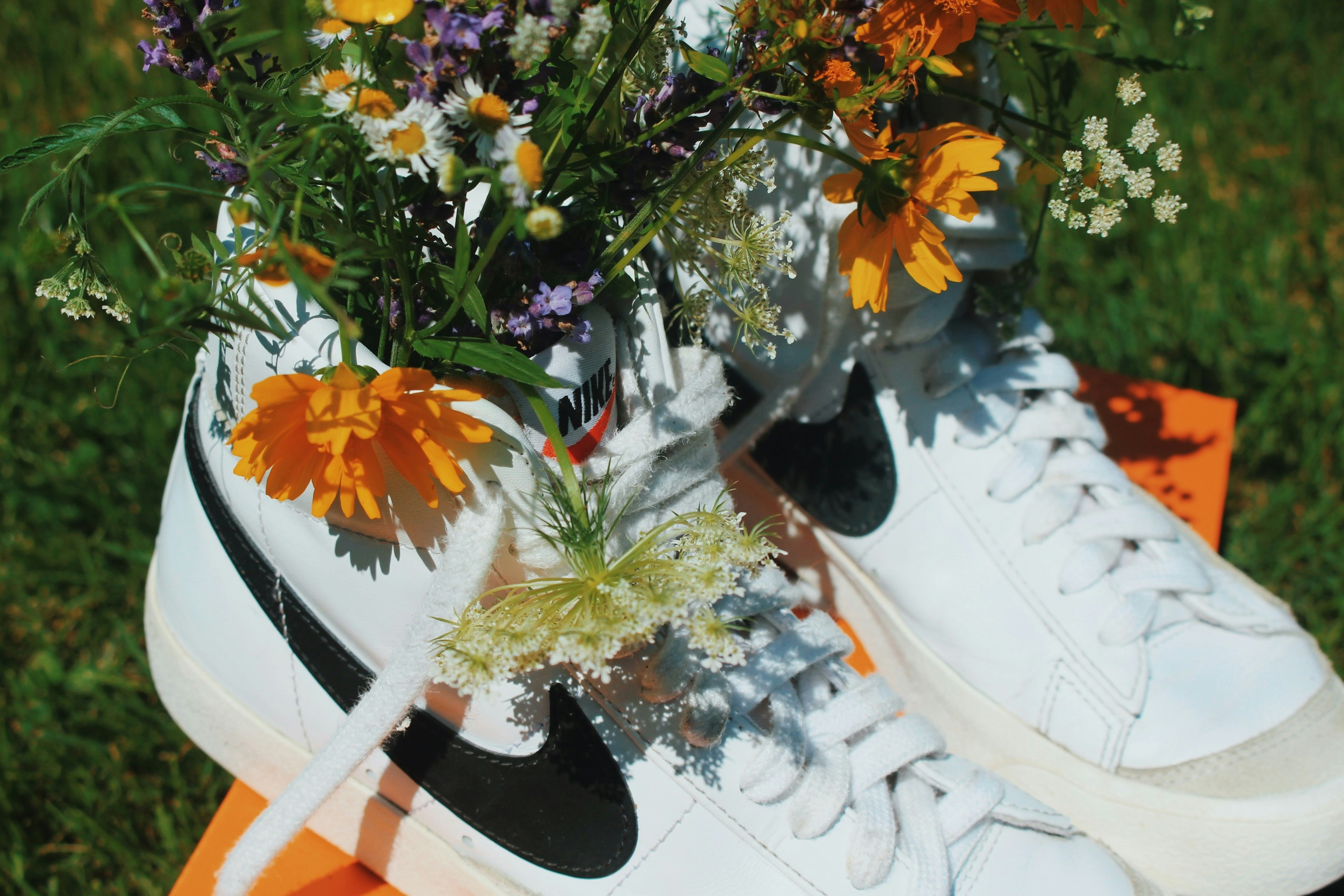 White sneakers filled with colorful wildflowers on an orange box