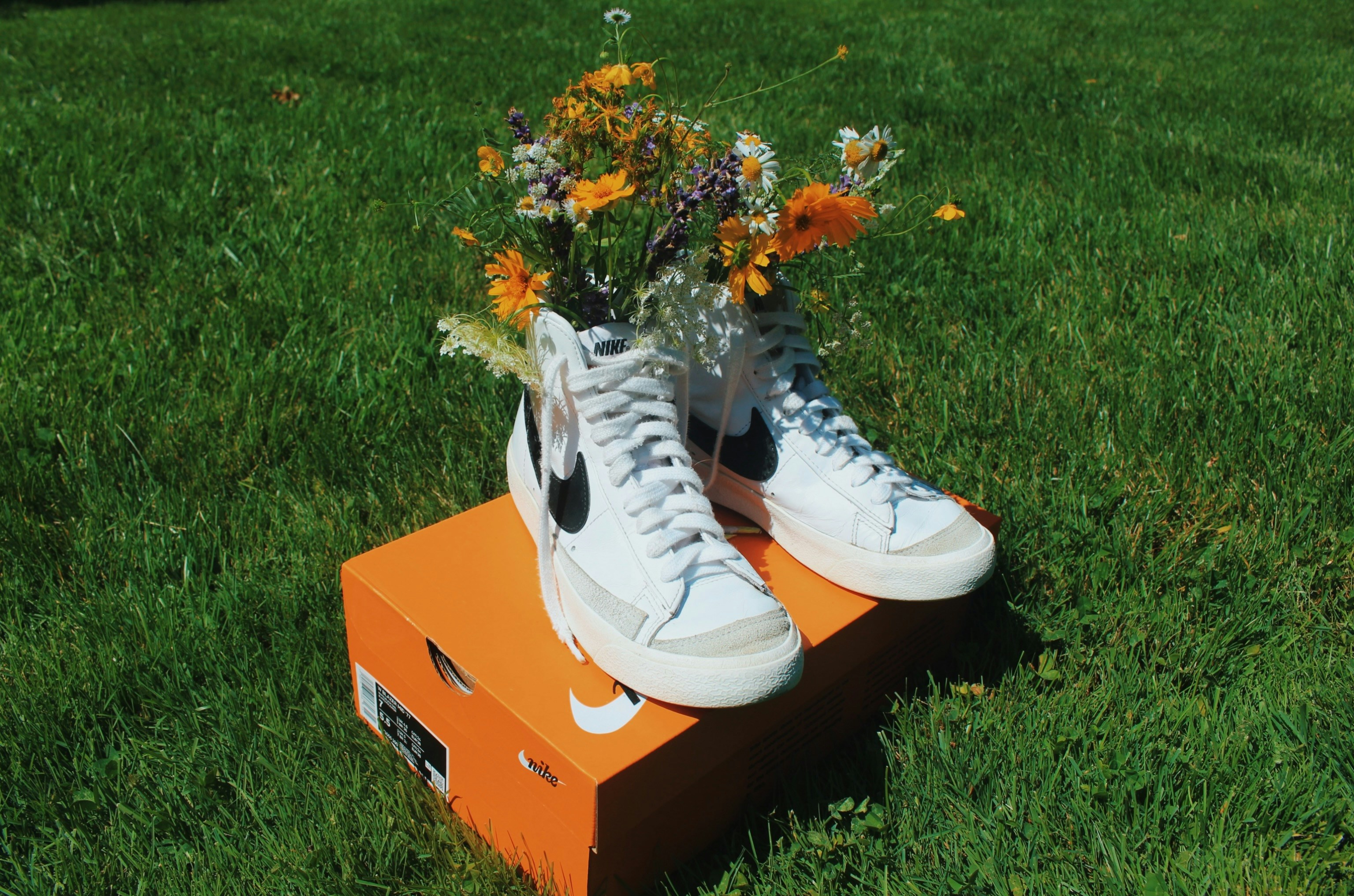 White sneakers with flowers on an orange box in grass