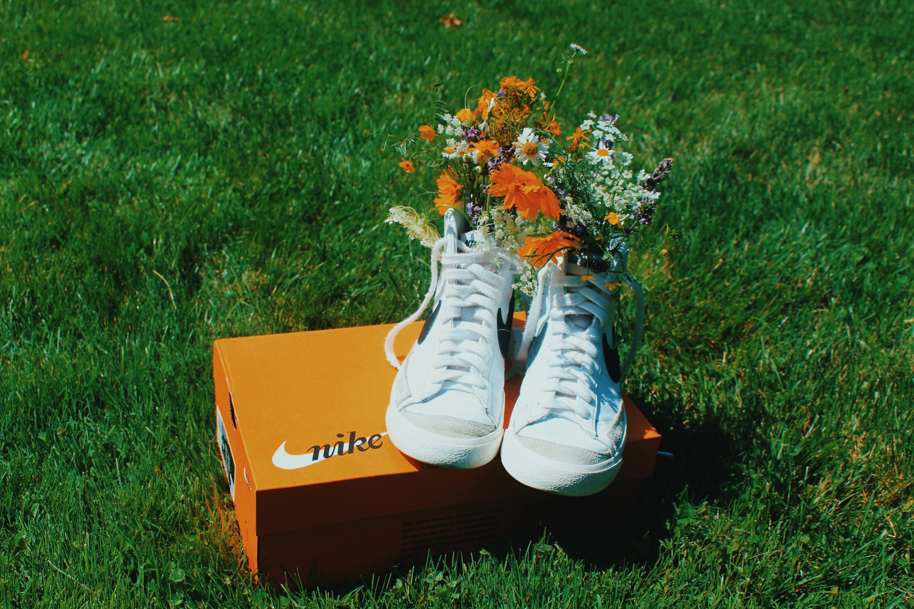 White sneakers with flowers on a nike box in grass
