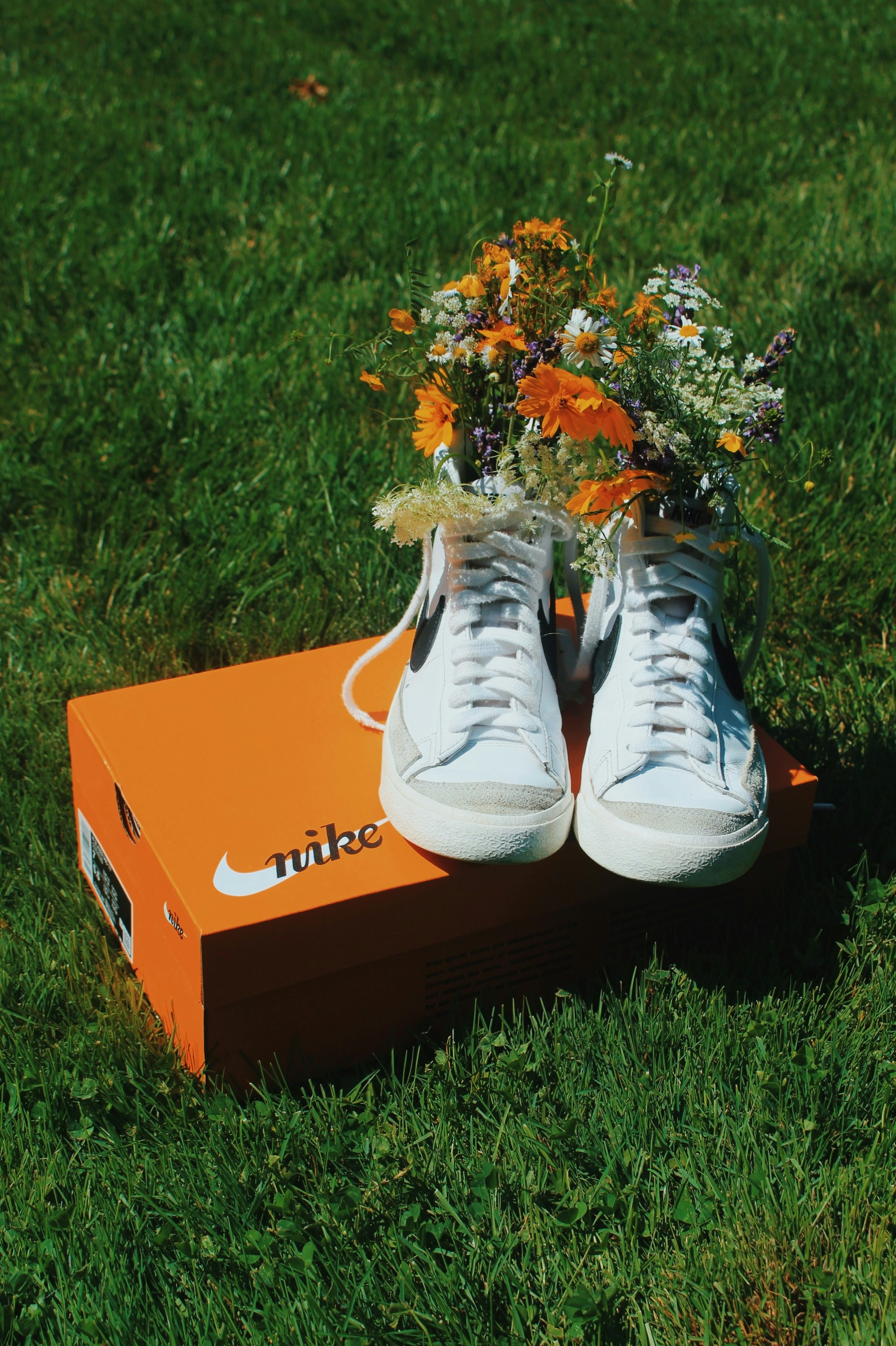 White nike sneakers filled with wildflowers on an orange shoebox
