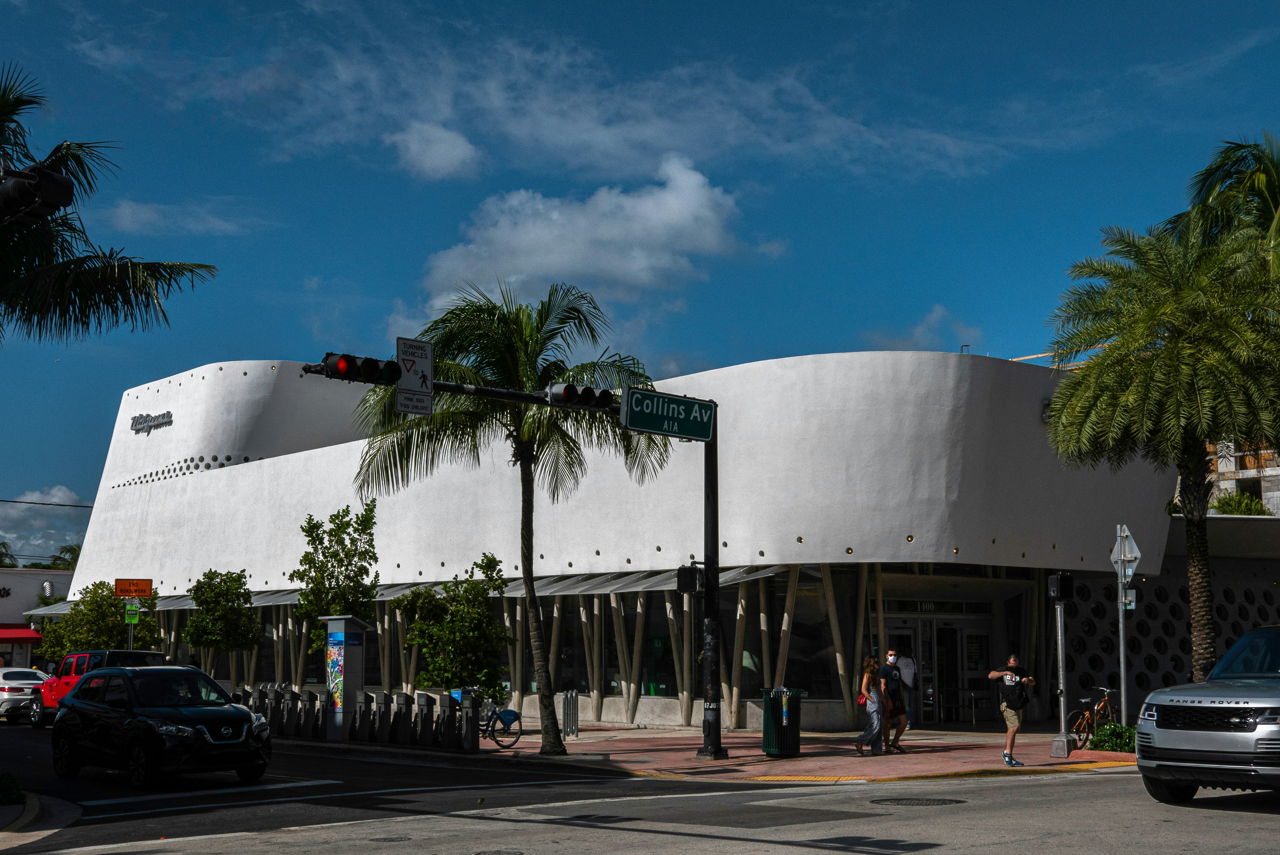 A modern white building with curved walls and palm trees.