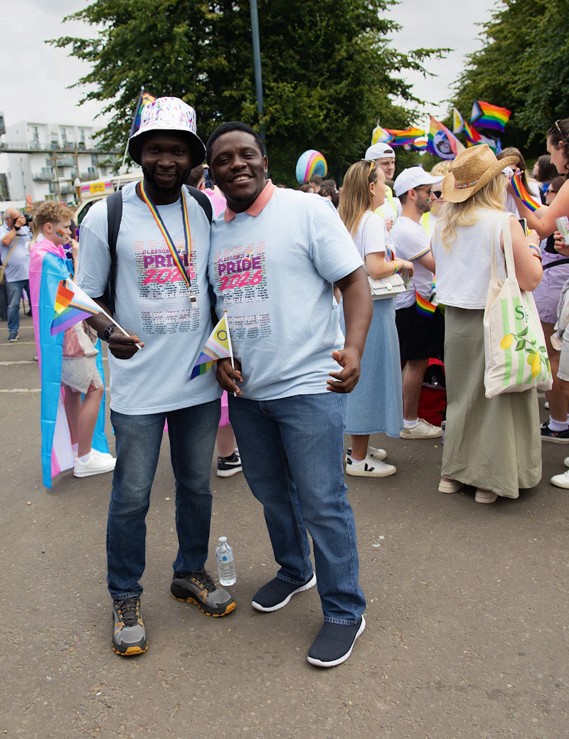 Two Black men standing together and smiling at a Pride event