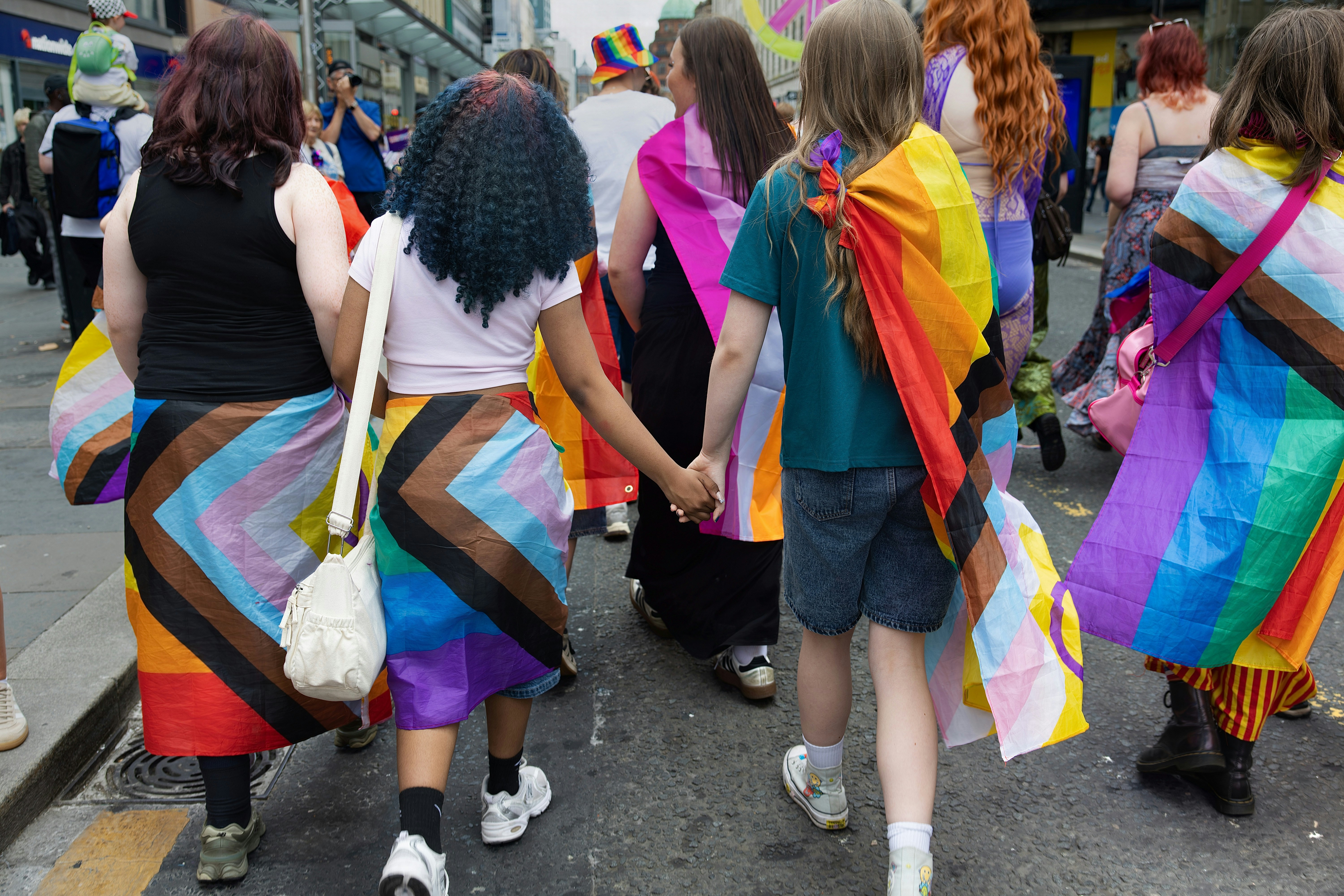Participantes de um desfile do orgulho exibindo cores vibrantes do arco-íris