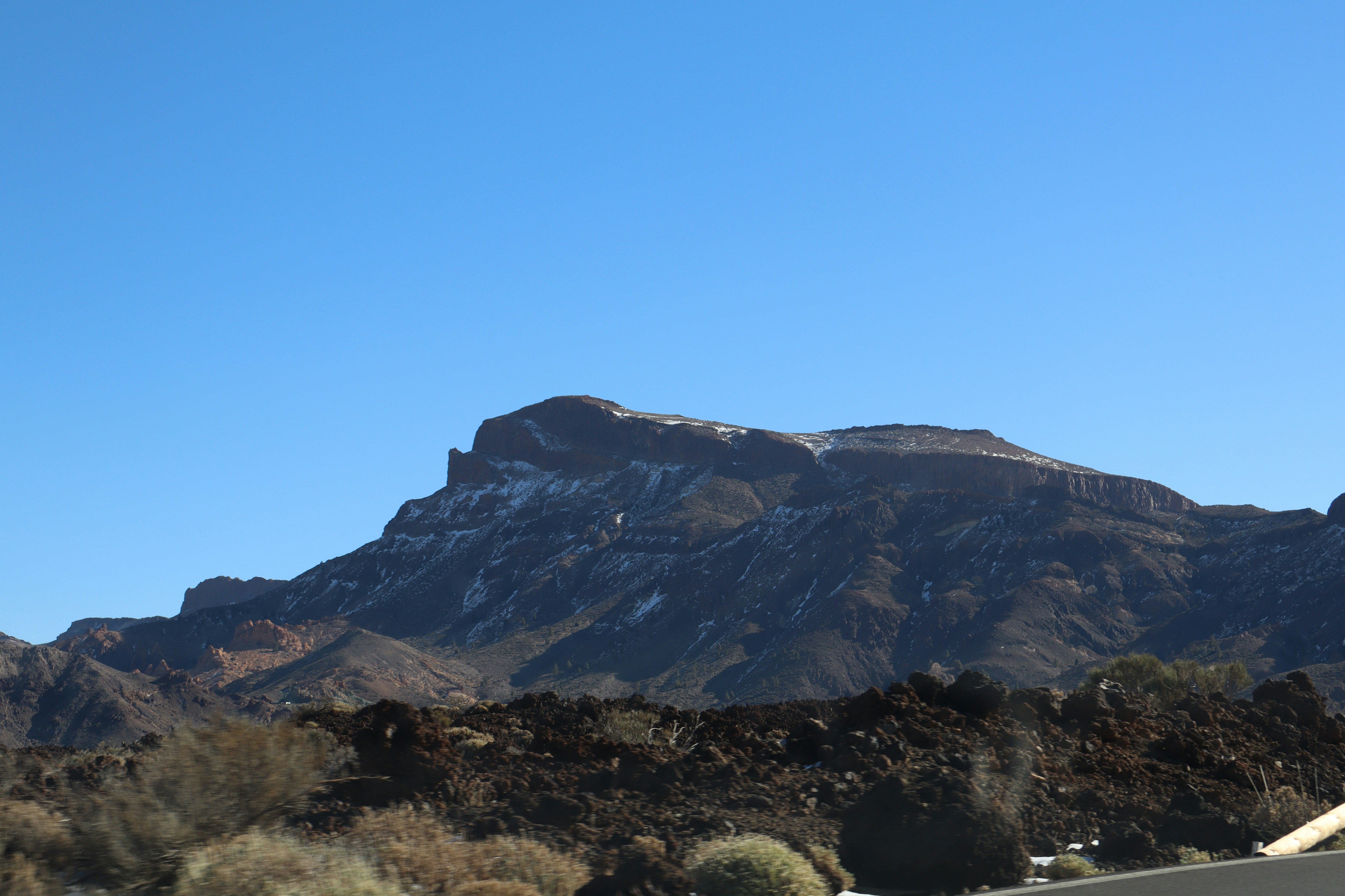 Mountain with snow and rocky terrain under blue sky