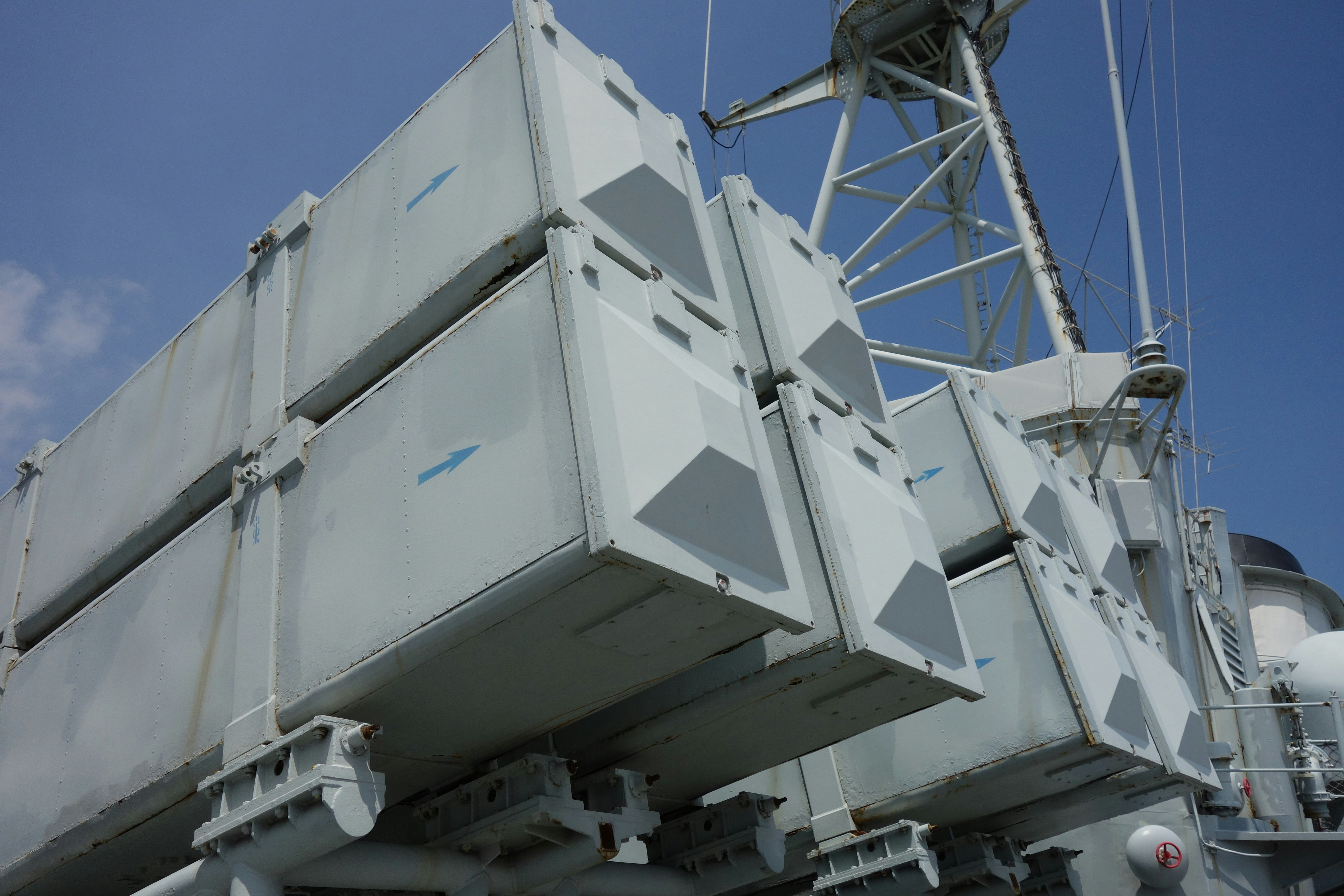 Warship missile launchers under a clear blue sky.
