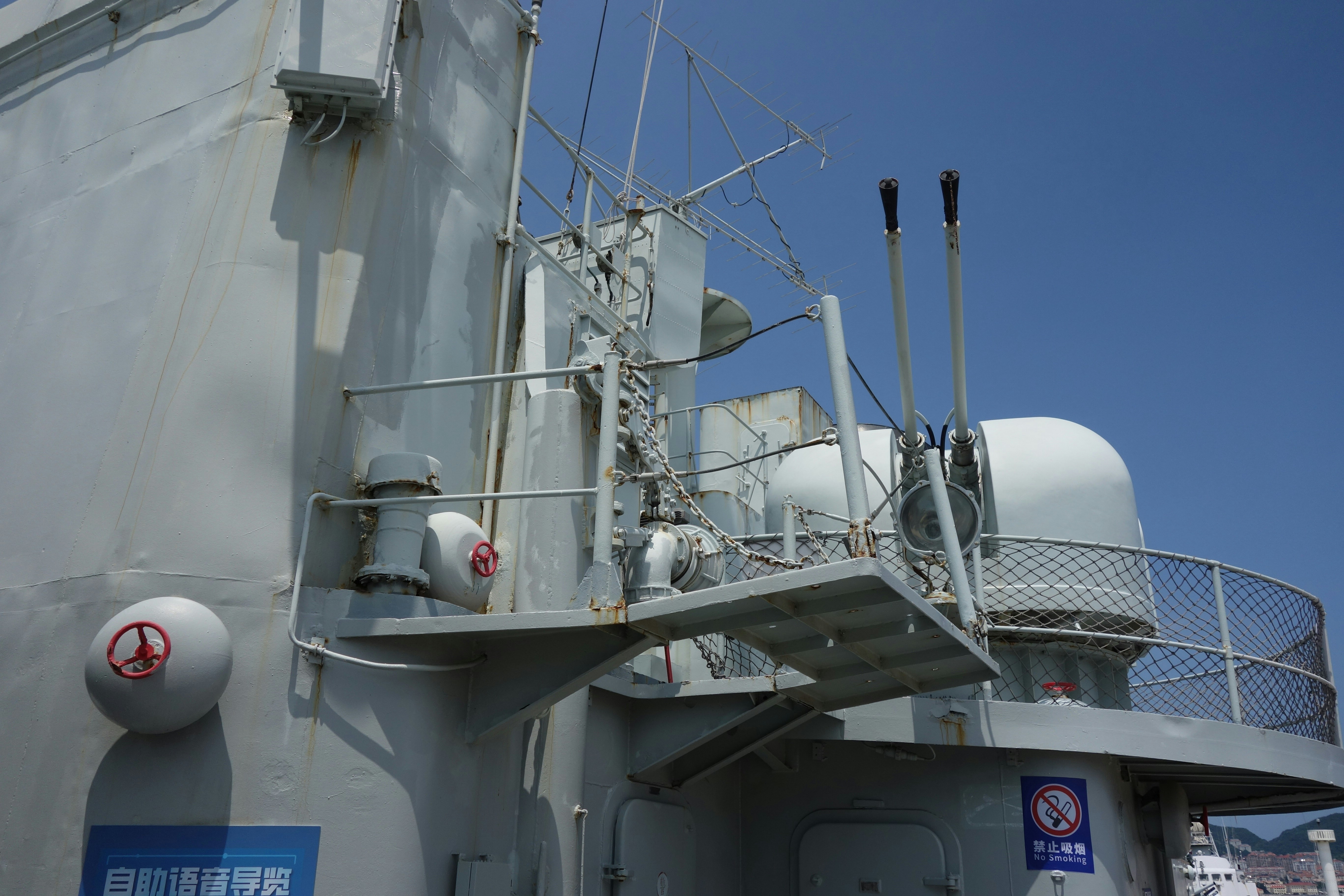 Warship's grey deck featuring radar and weapon systems.
