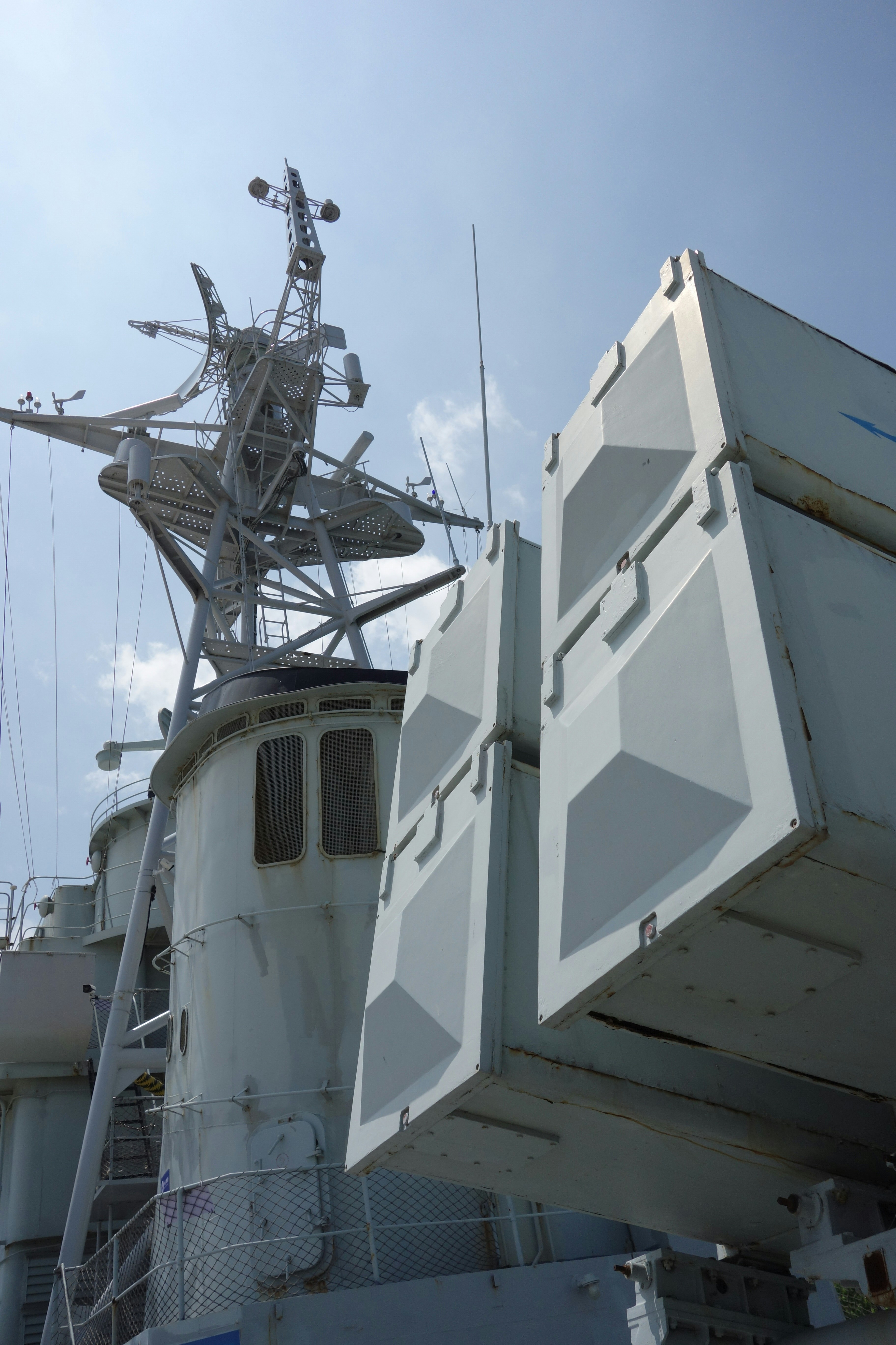 Warship mast and missile launchers against a blue sky.