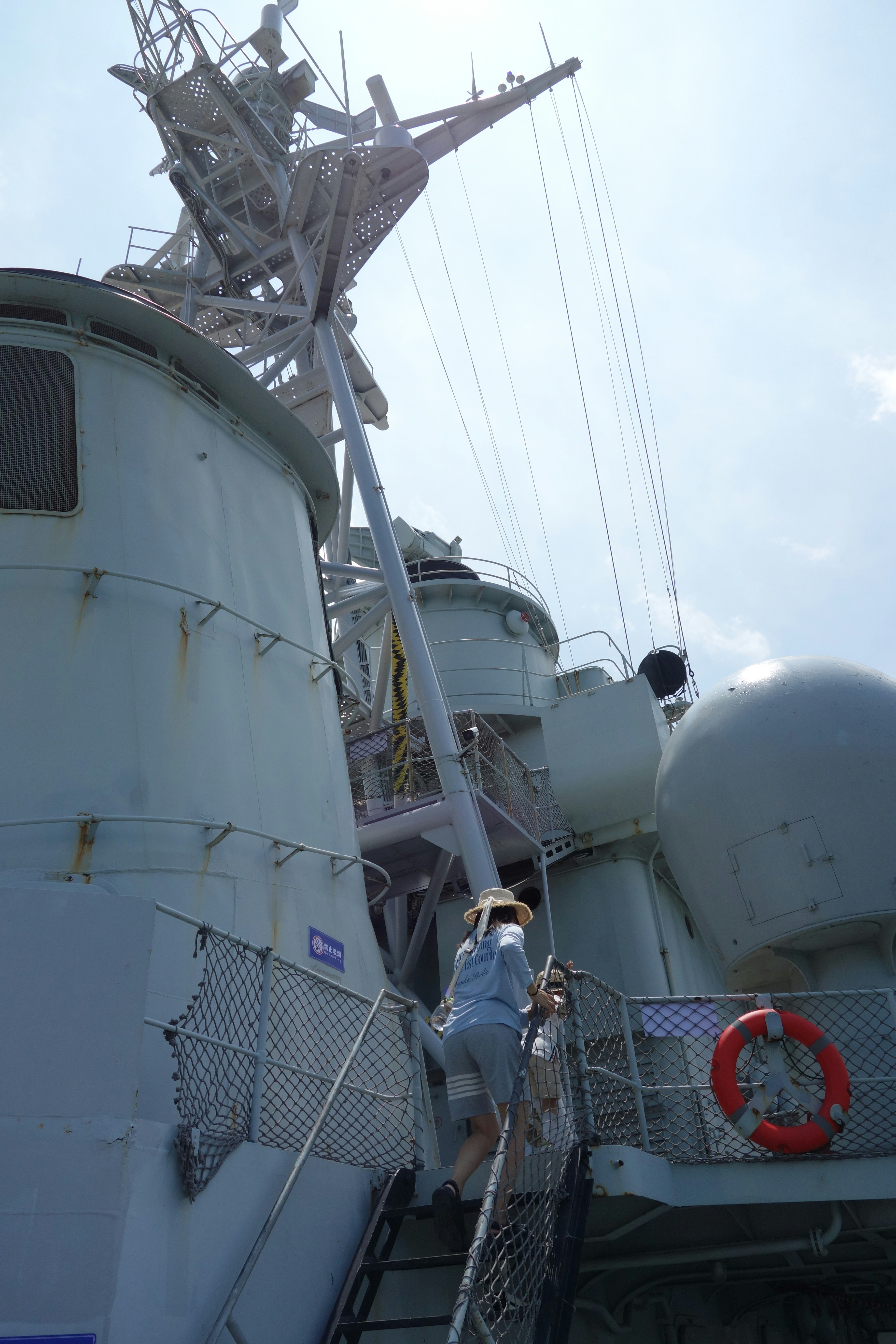 A person climbs stairs on a large grey warship.