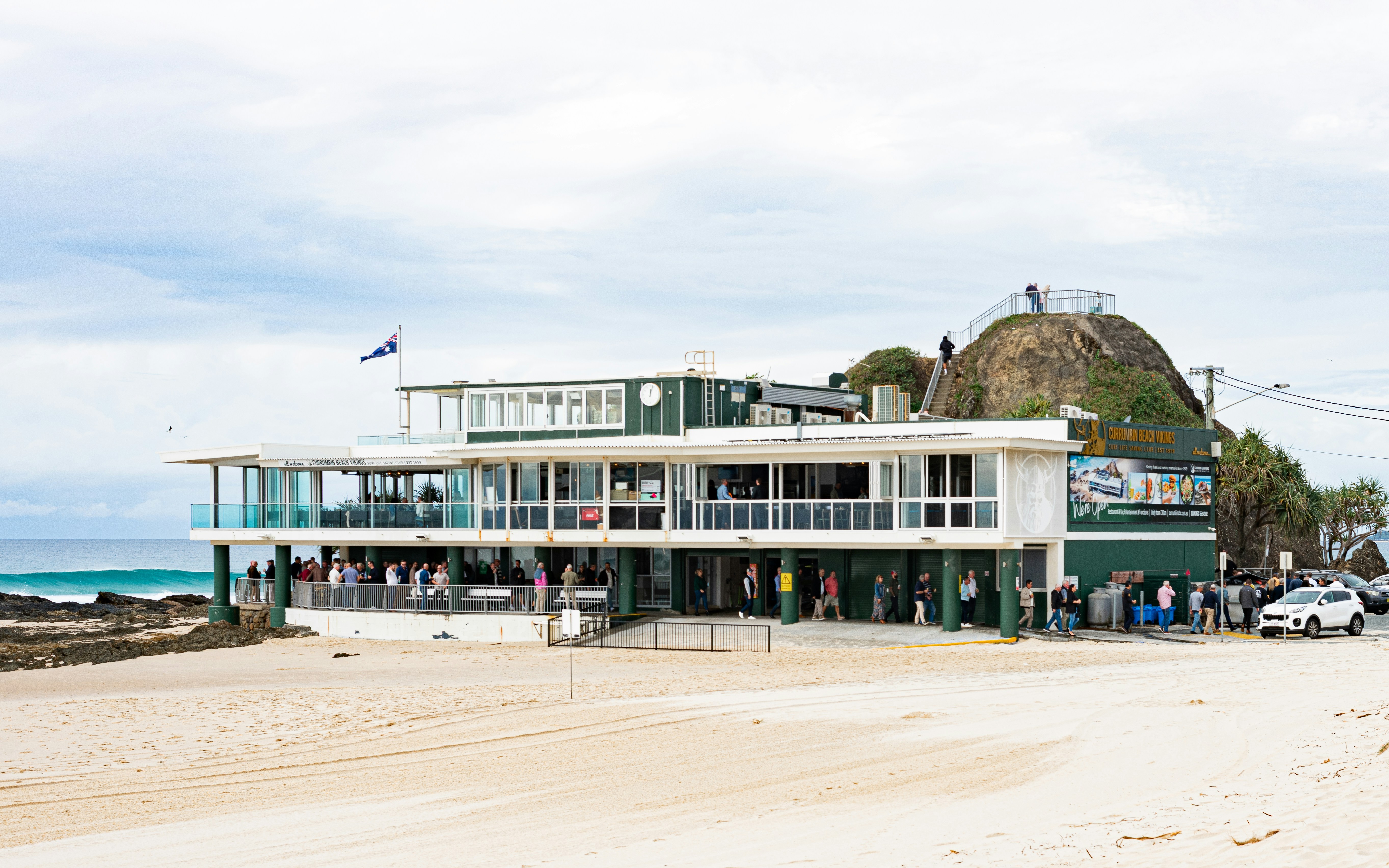 A two-story building on a sandy beach by the ocean