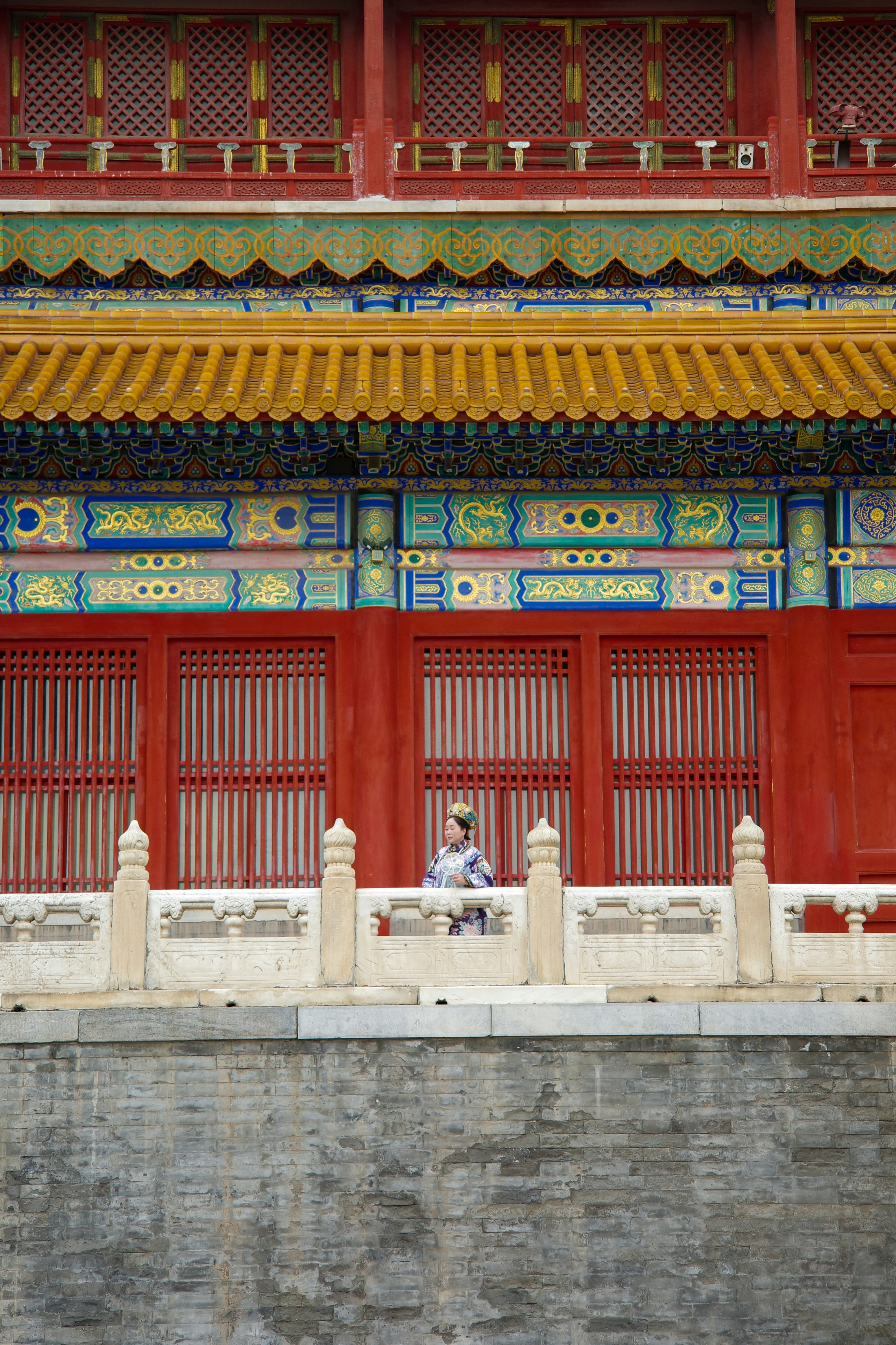 Woman on balcony of colorful traditional chinese building.