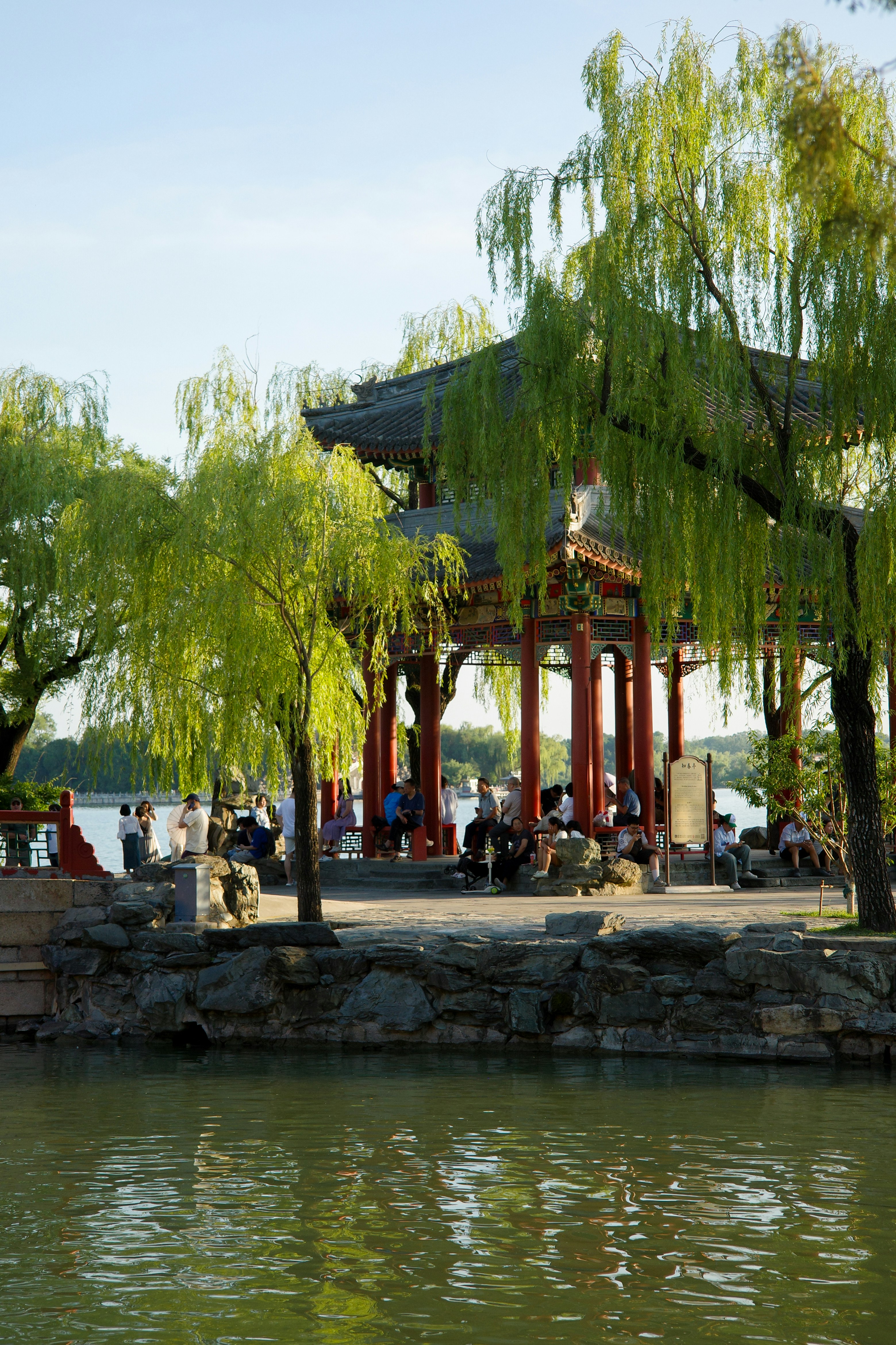 Traditional chinese pavilion by water with weeping willow trees.