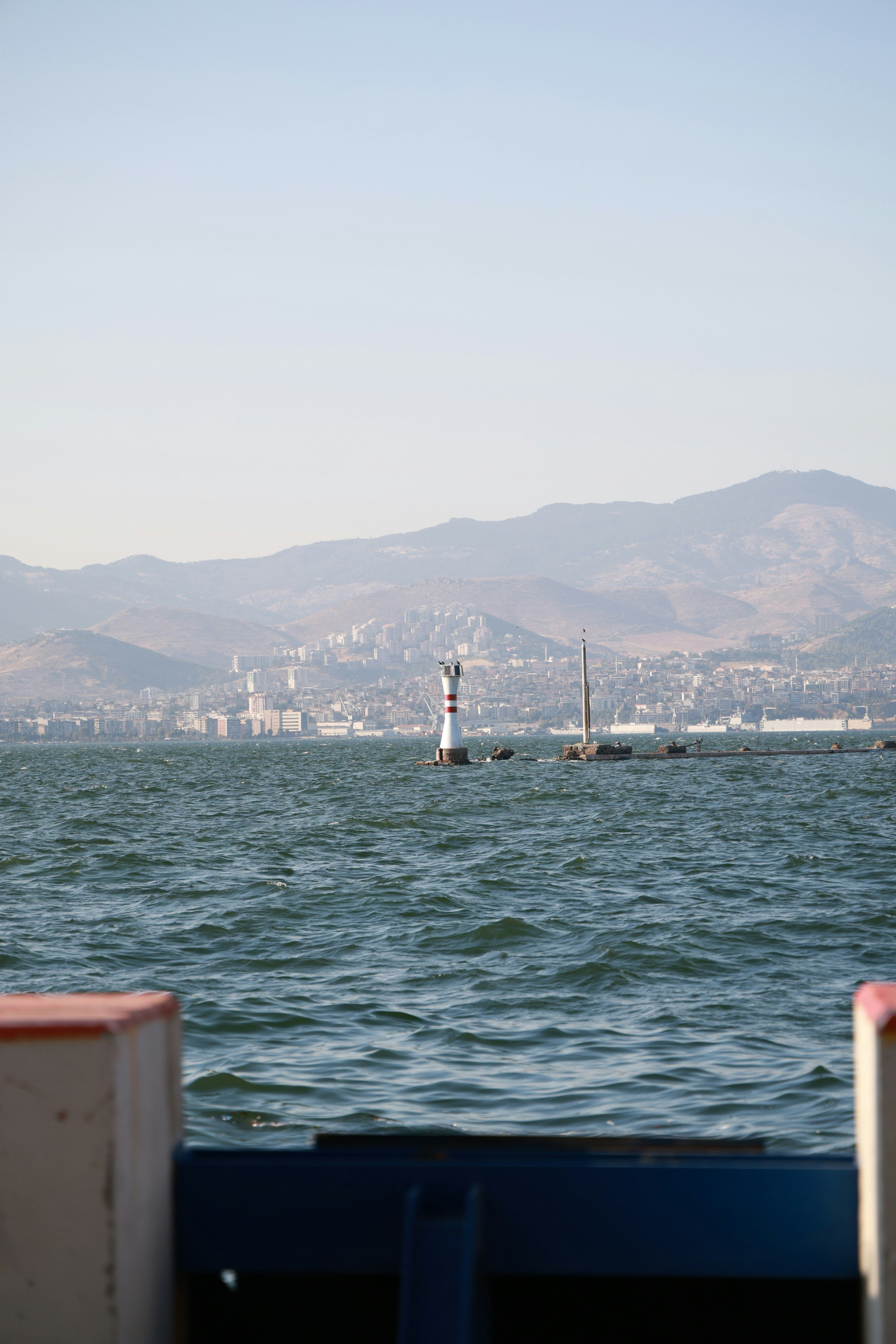 Faro in mare con montagne lontane e una città