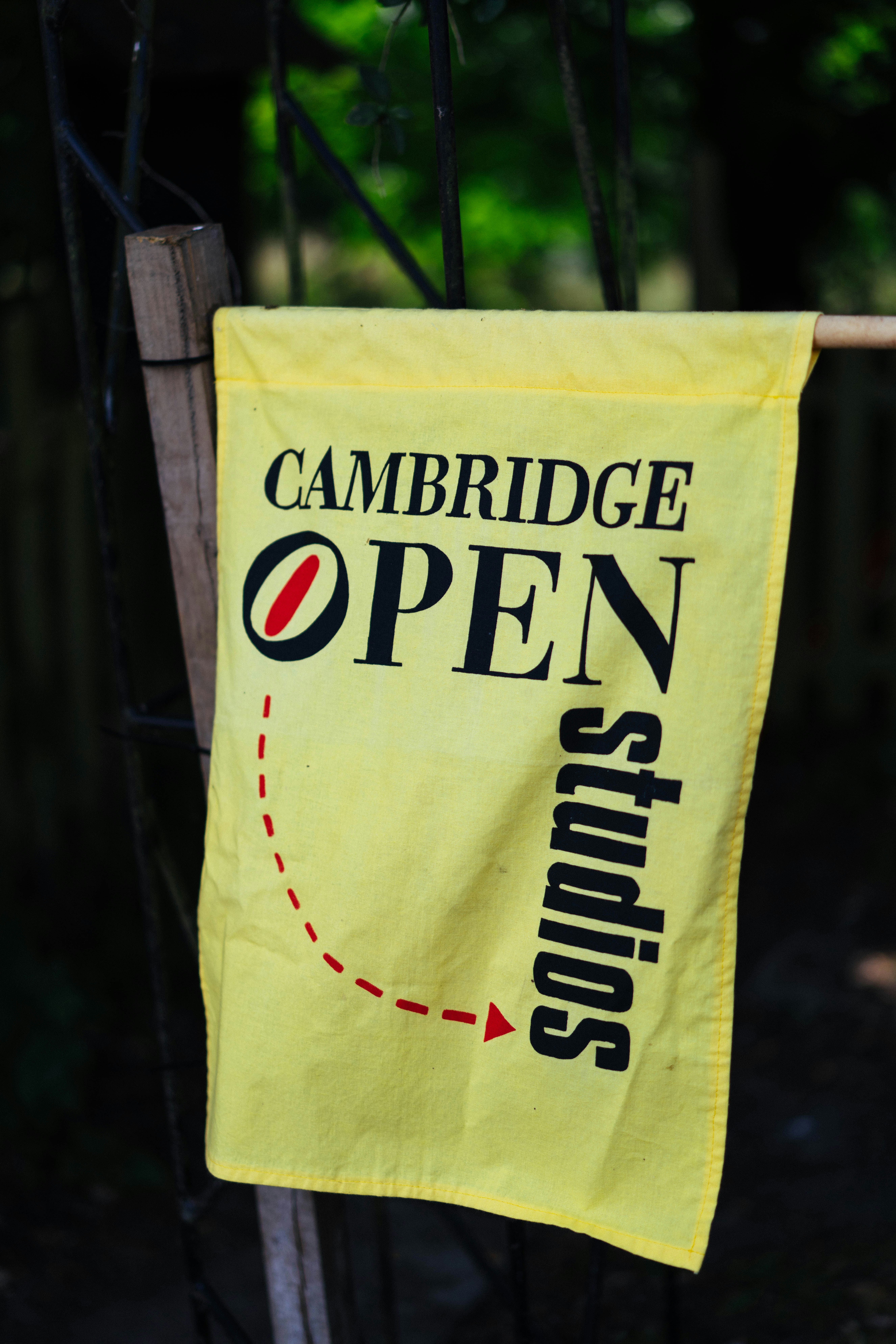 A yellow flag for cambridge open studios hangs outdoors.