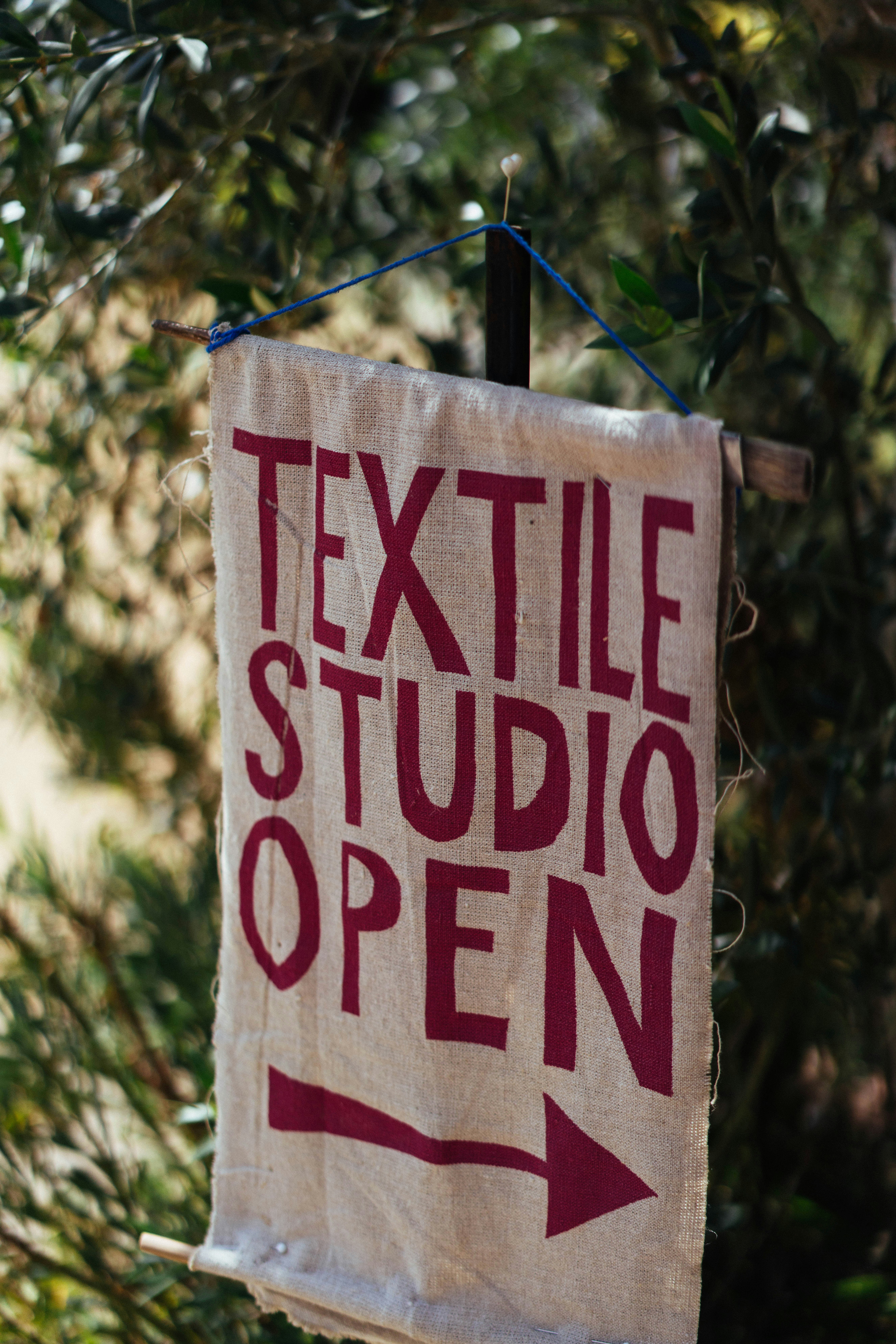 A handmade "textile studio open" sign with an arrow.