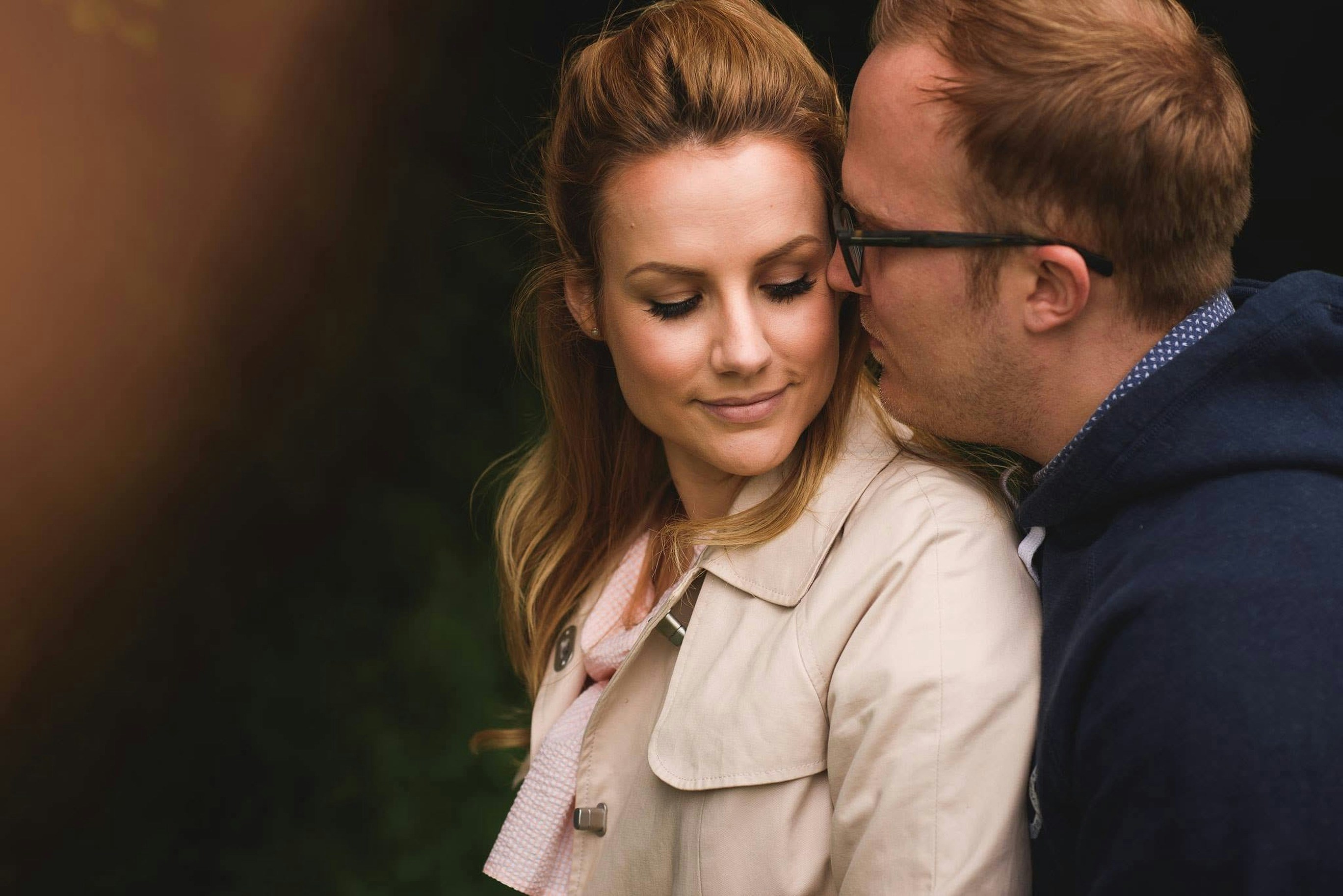 A man whispers to a woman outdoors