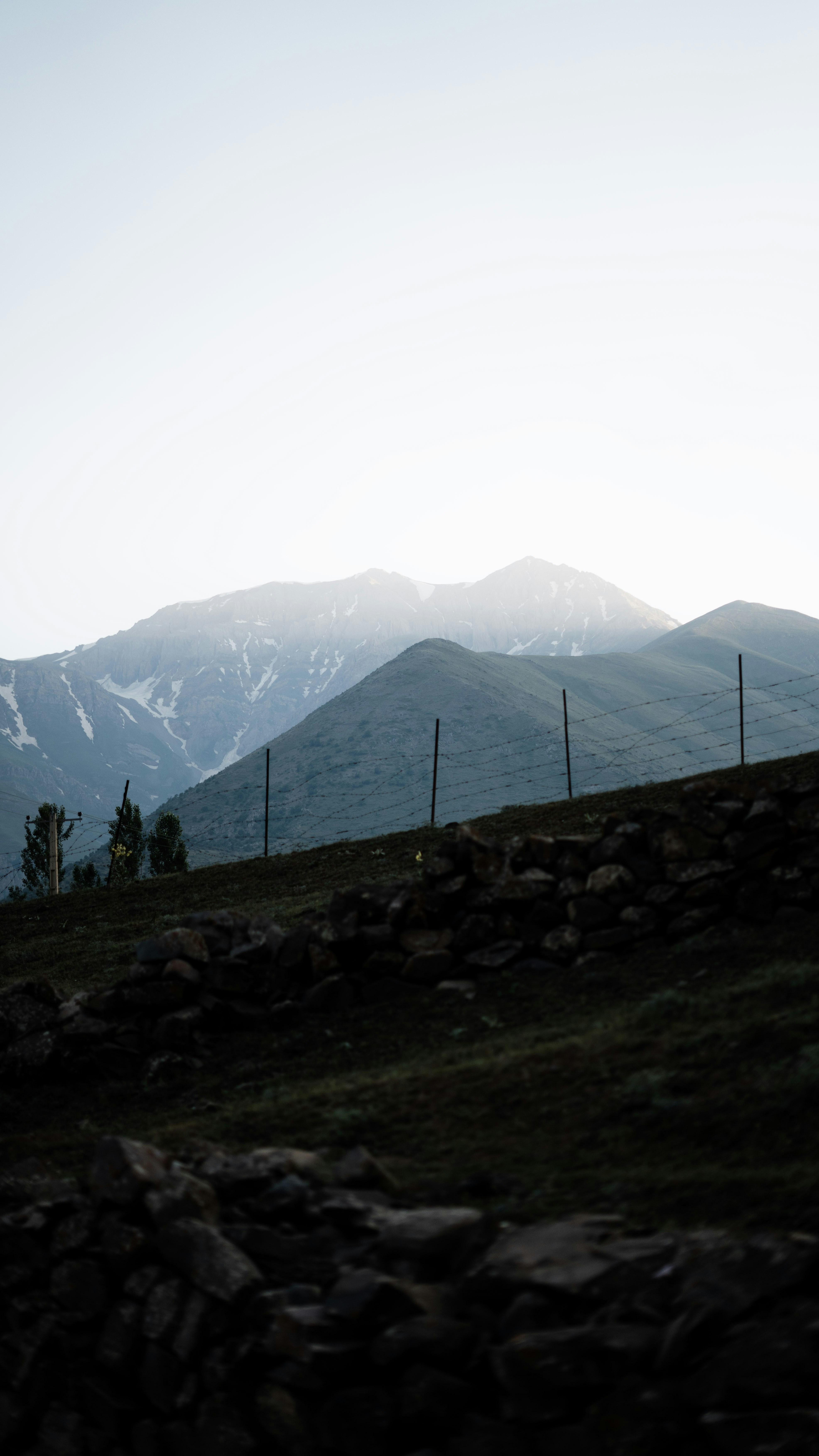 Hazy mountains rise above a dark, rocky hillside.