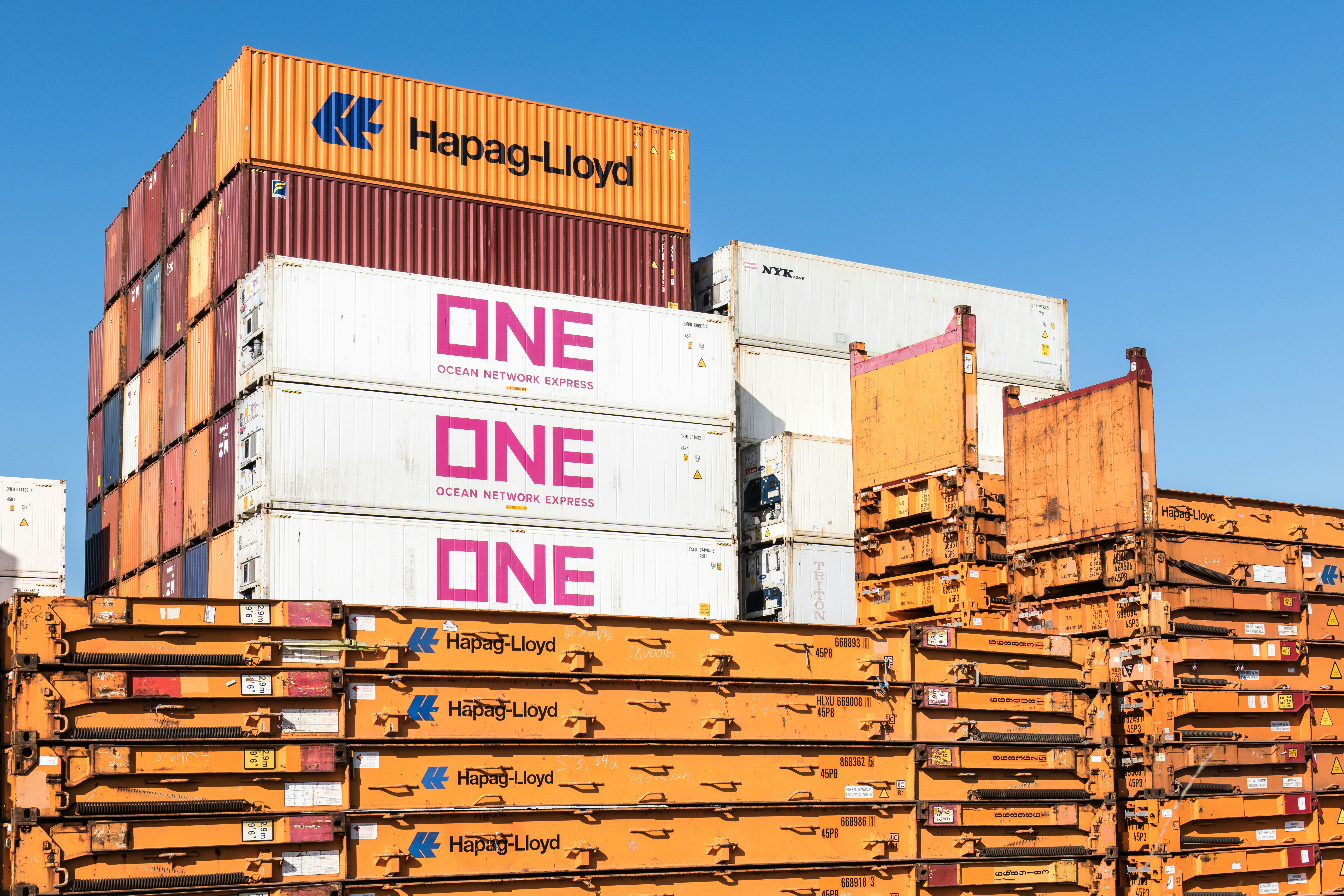 Hapag-Lloyd und ein Container vor blauem Himmel gestapelt.
