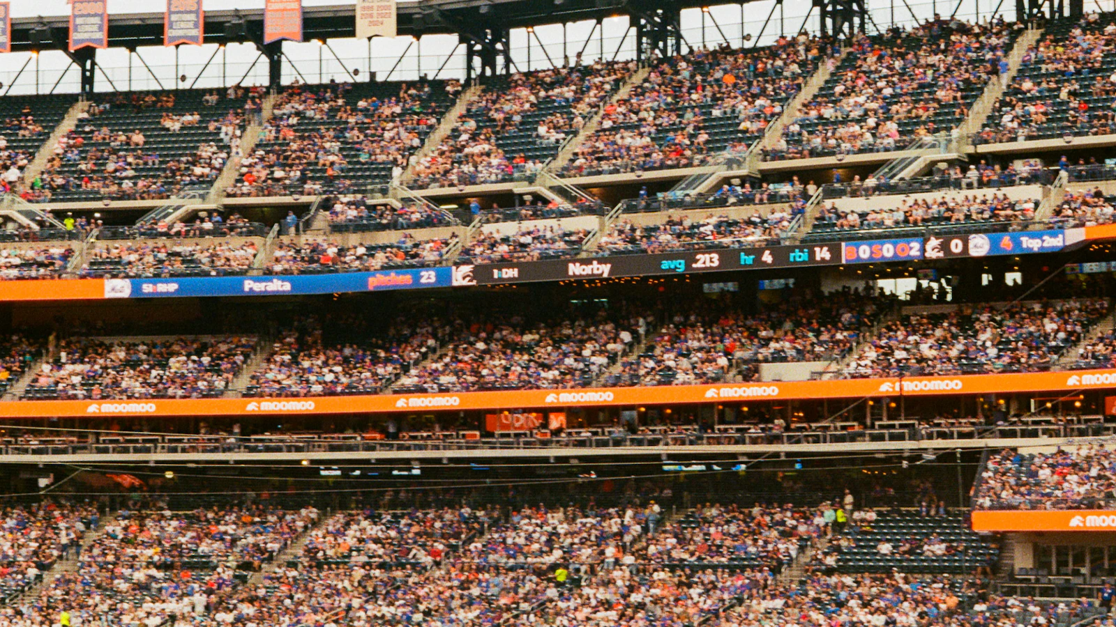 A crowded baseball stadium under bright lights during a game A crowded baseball stadium under bright lights during a game