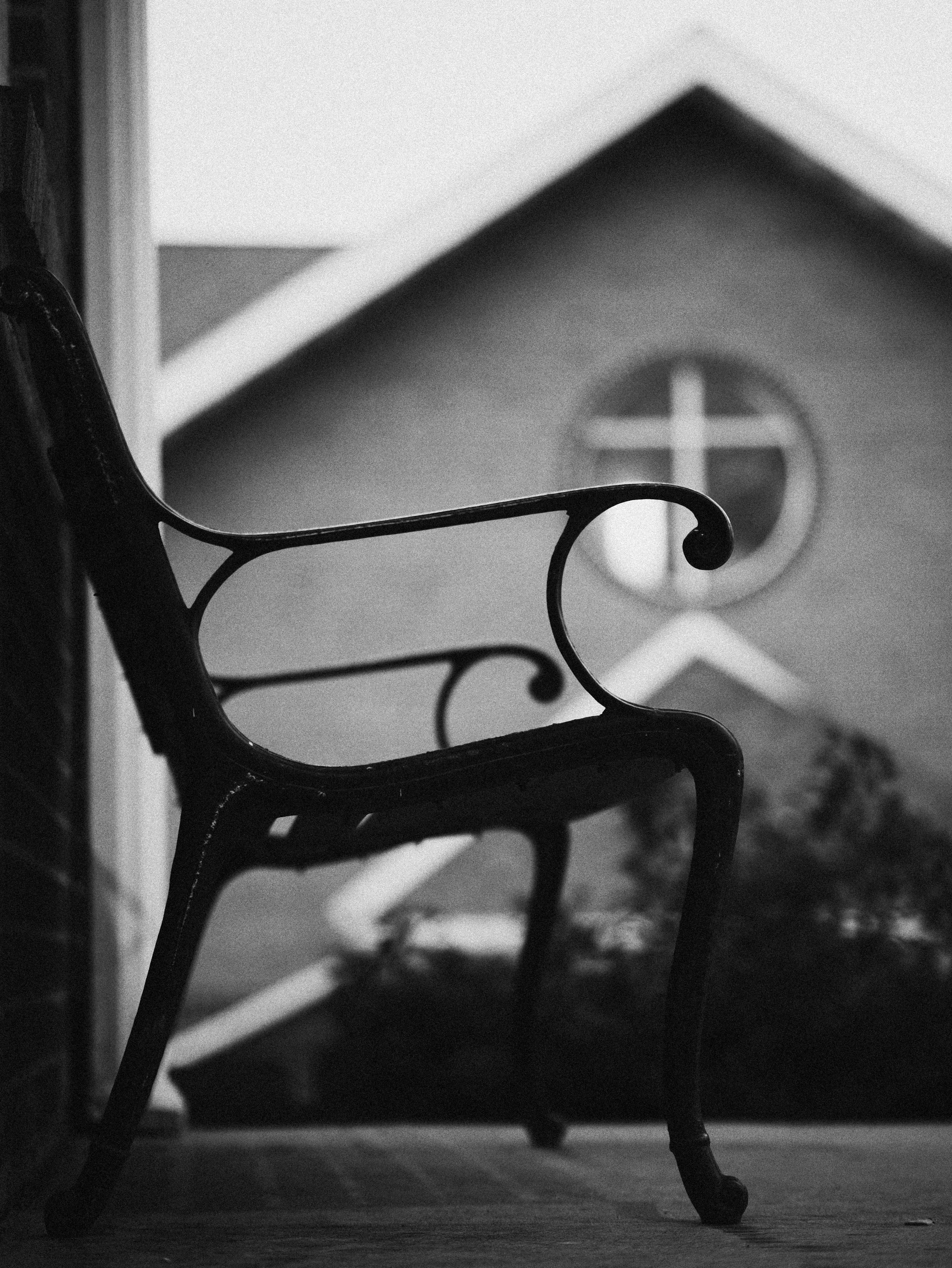 Ornate metal bench with building and cross-shaped window