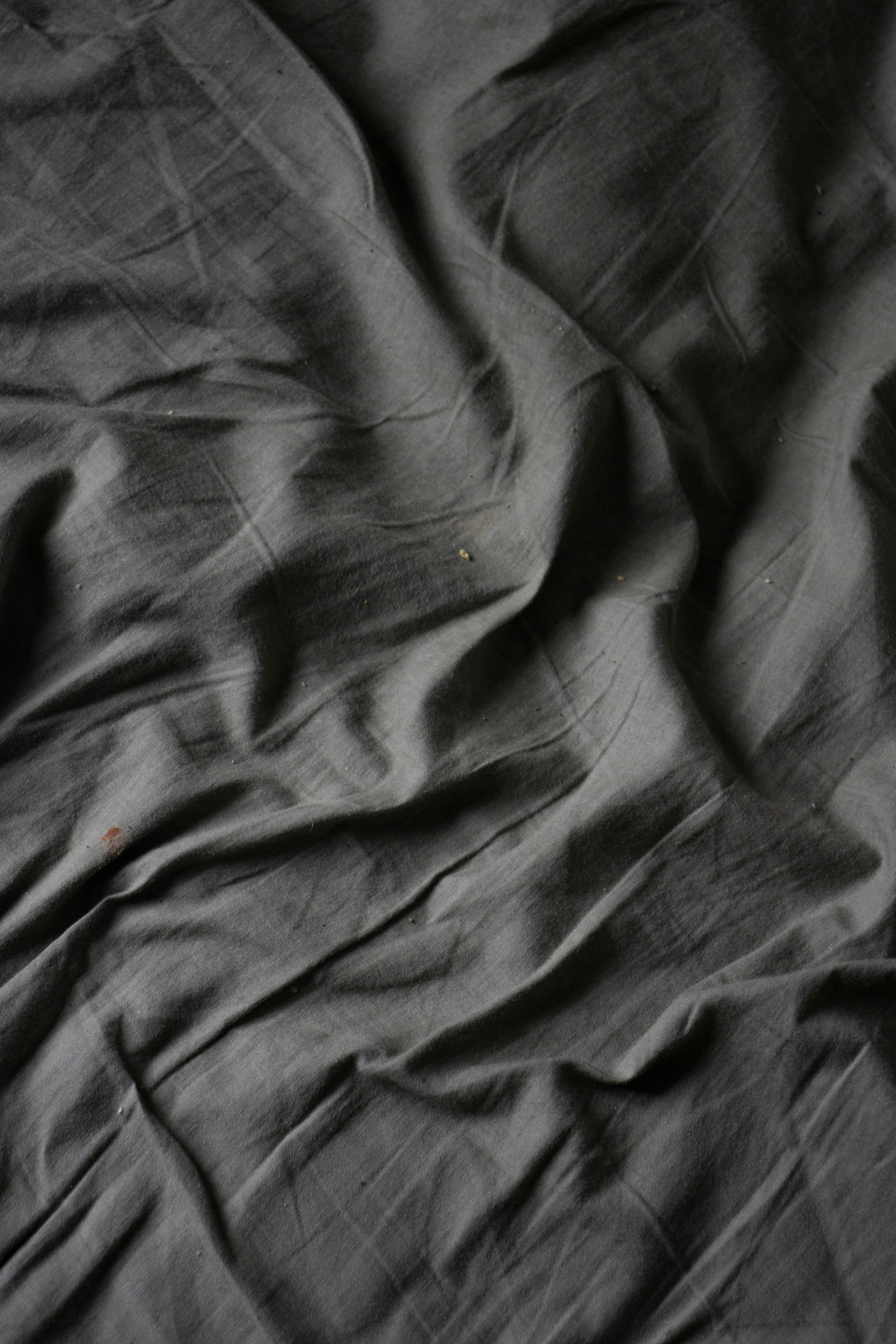 Tecido cinza escuro amassado, com dobras e sombras