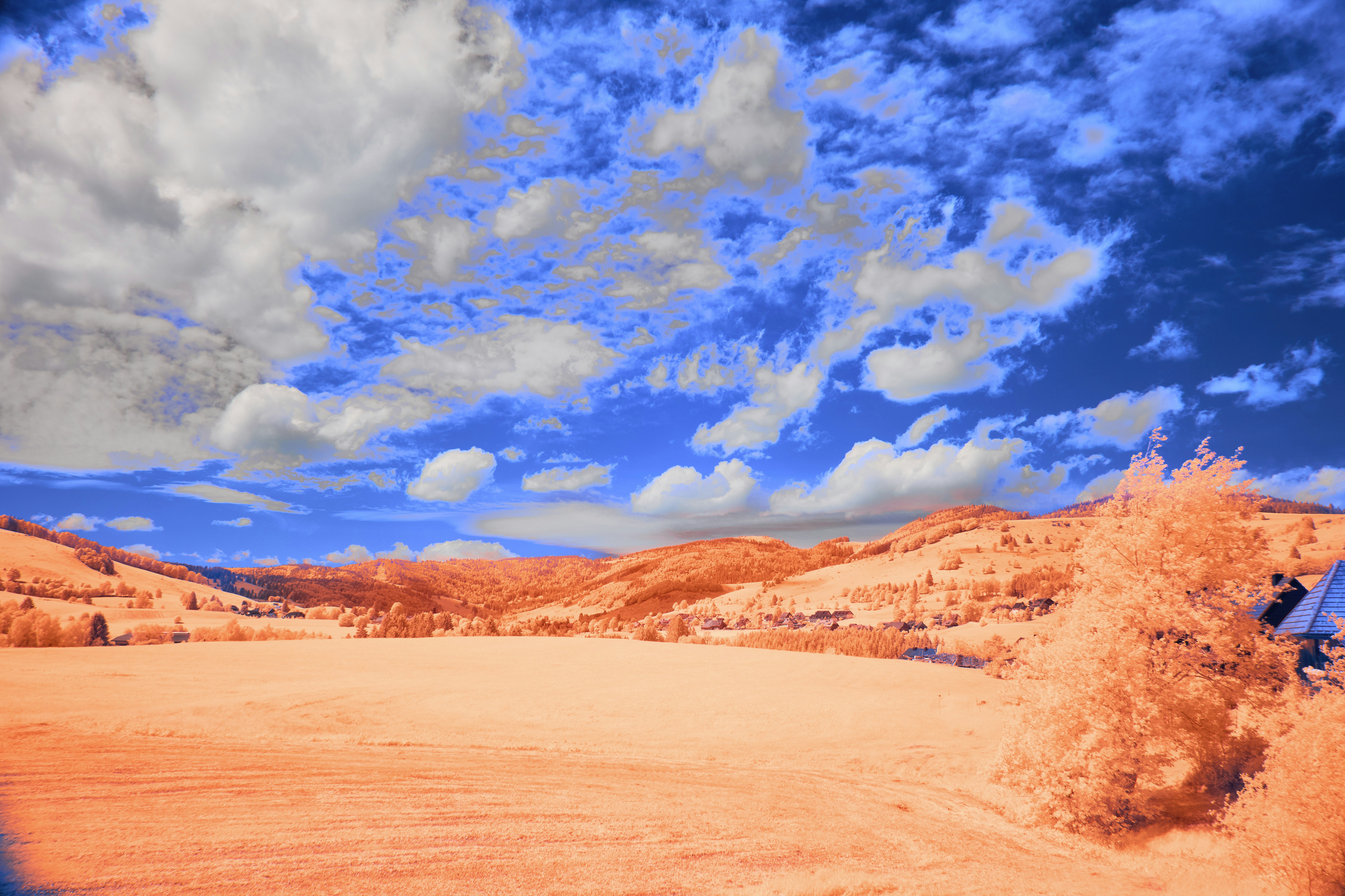Infrared landscape with vibrant blue sky and orange hills.