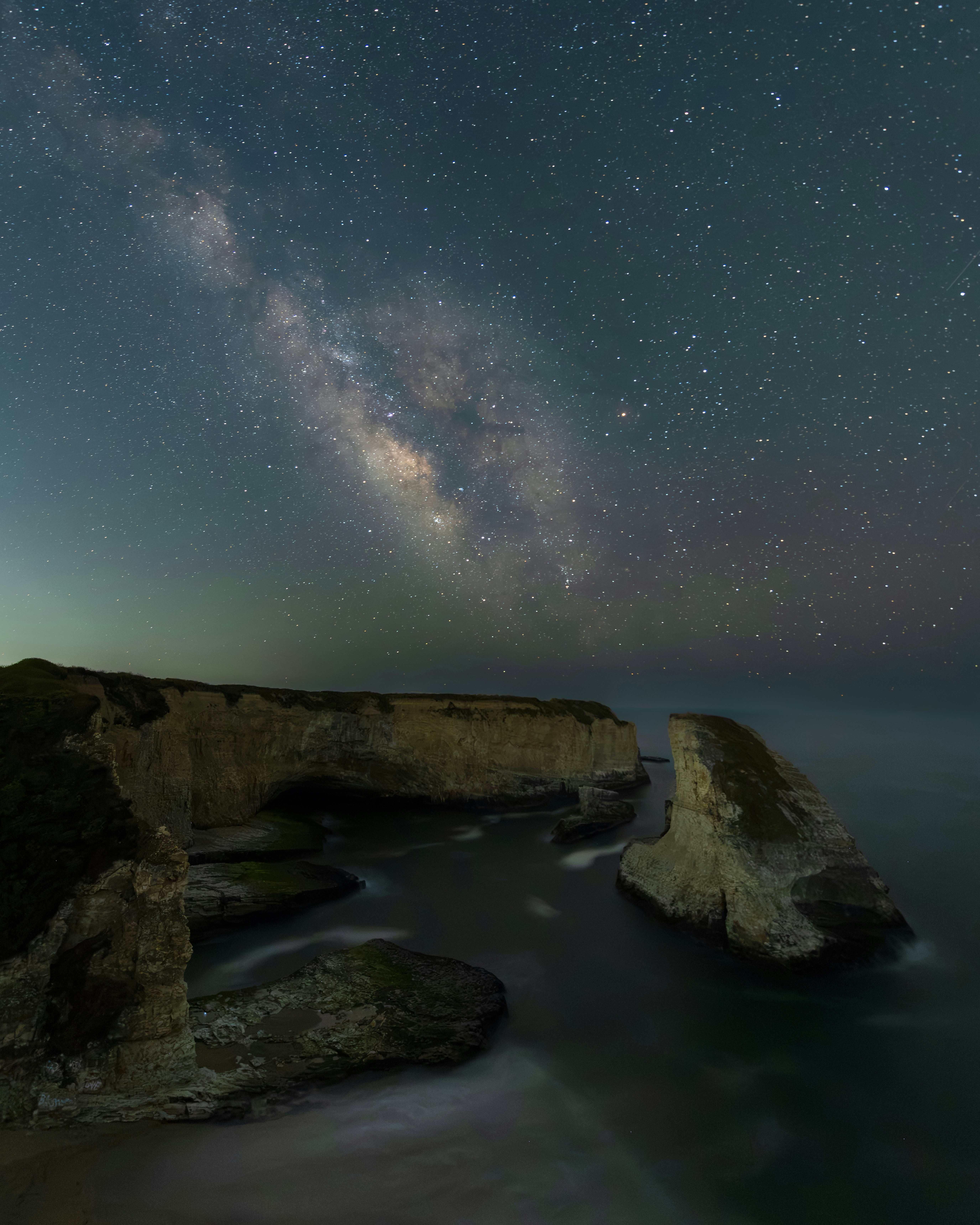 Milky way arching over coastal sea stacks