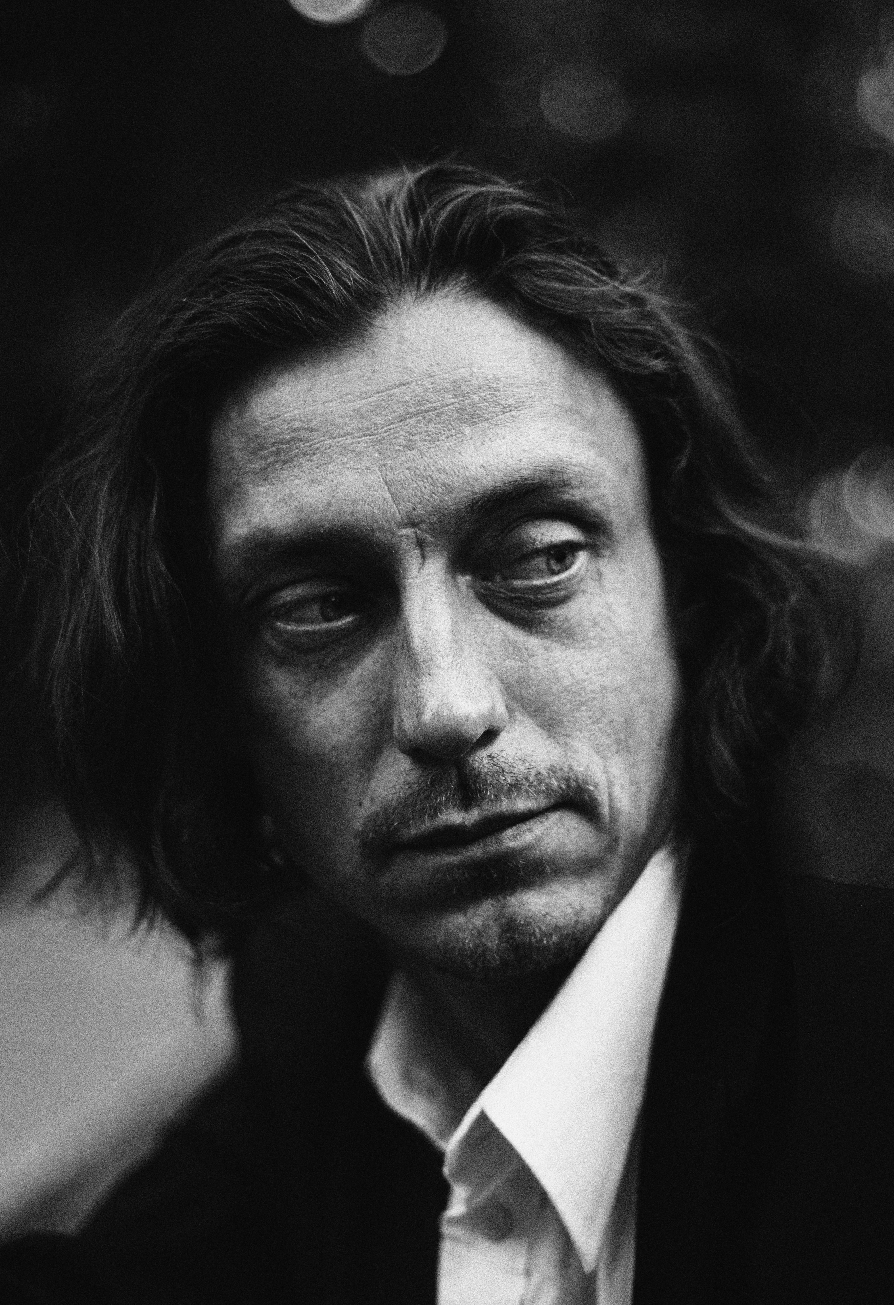 Man with long hair looking away in black and white.
