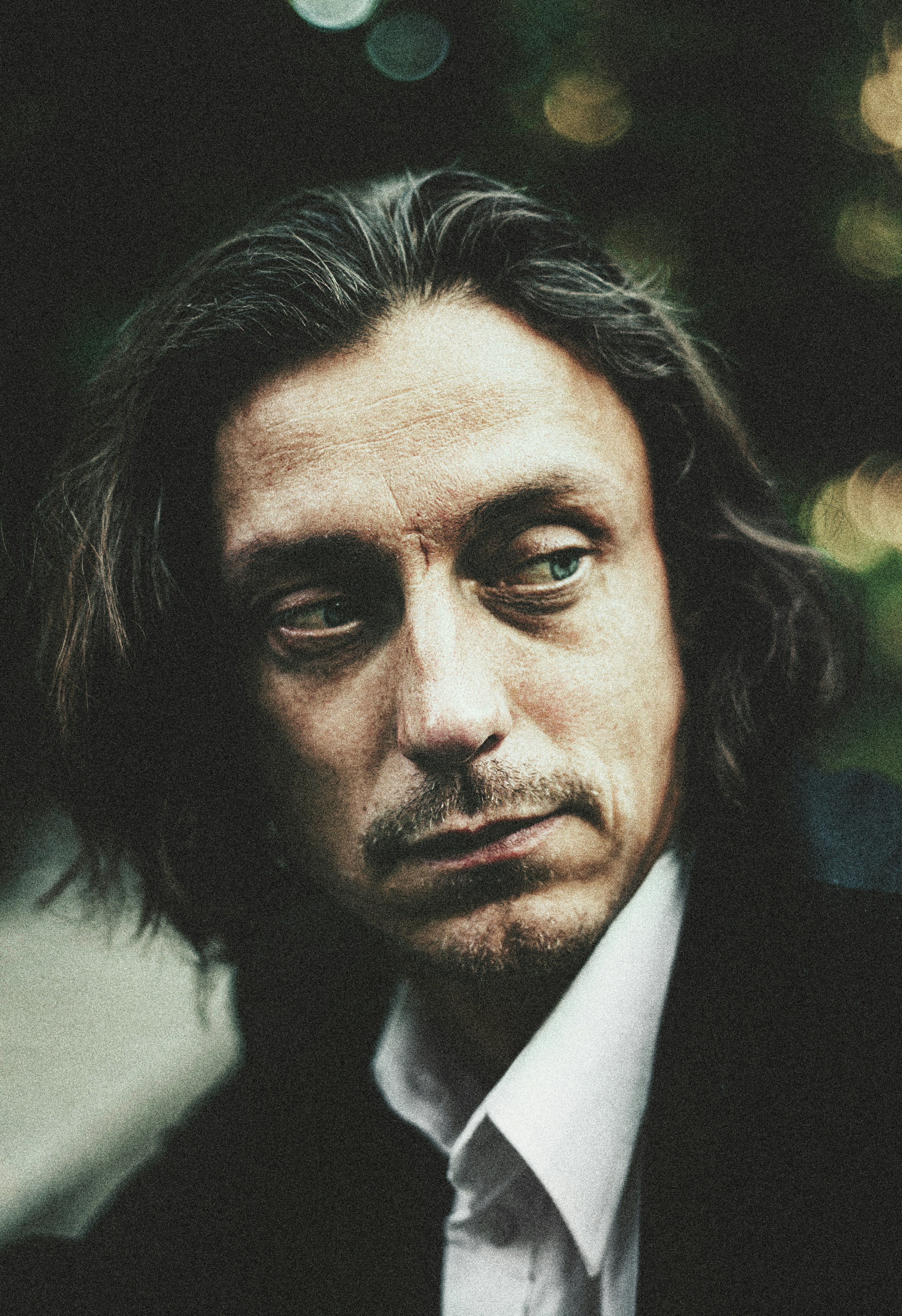 A man with long dark hair looking to the side.
