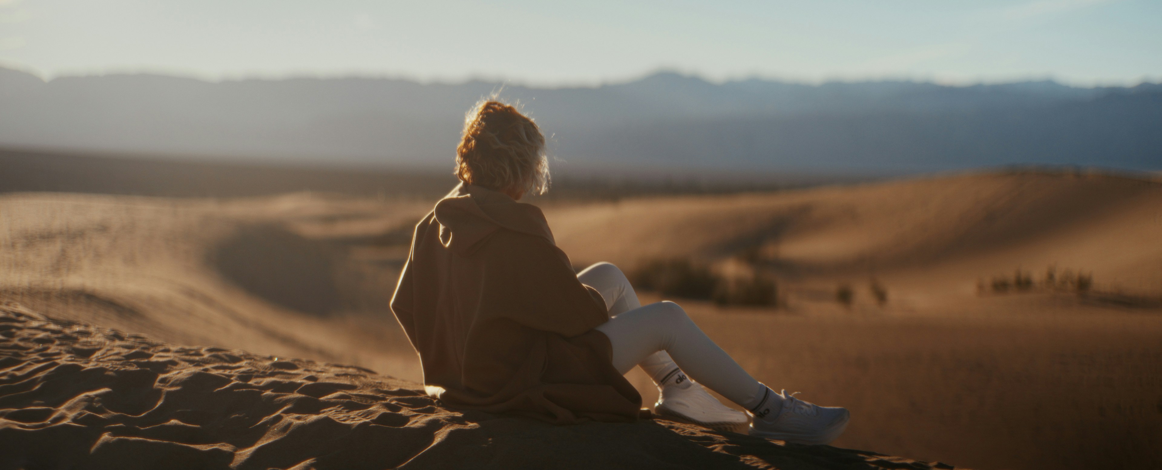Woman looking at vast desert landscape with dunes