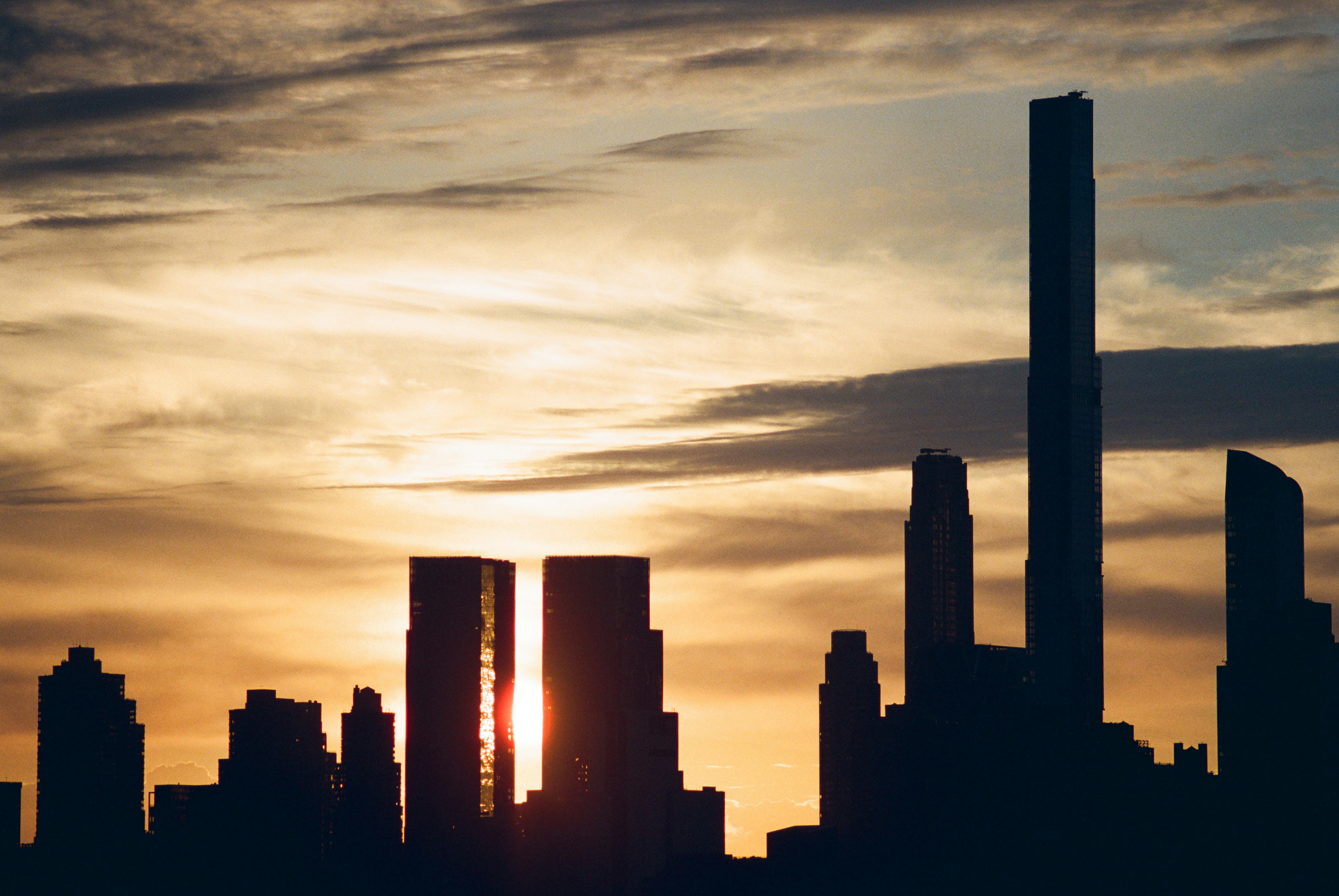 Dramatischer Sonnenuntergang hinter einer silhouettierten Stadtsilhouette