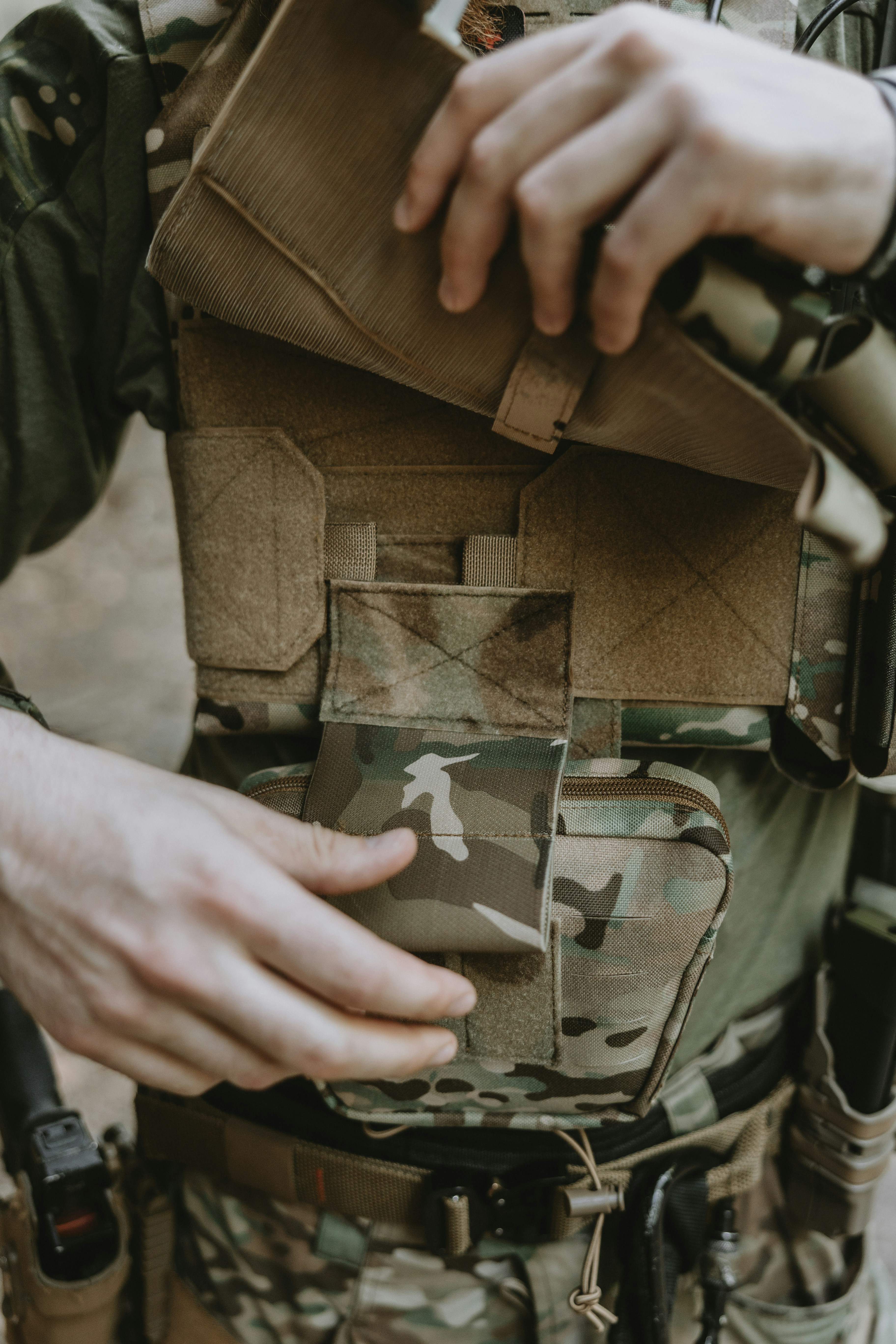 Close-up of a tactical plate carrier with a utility pouch during an outdoor airsoft game.