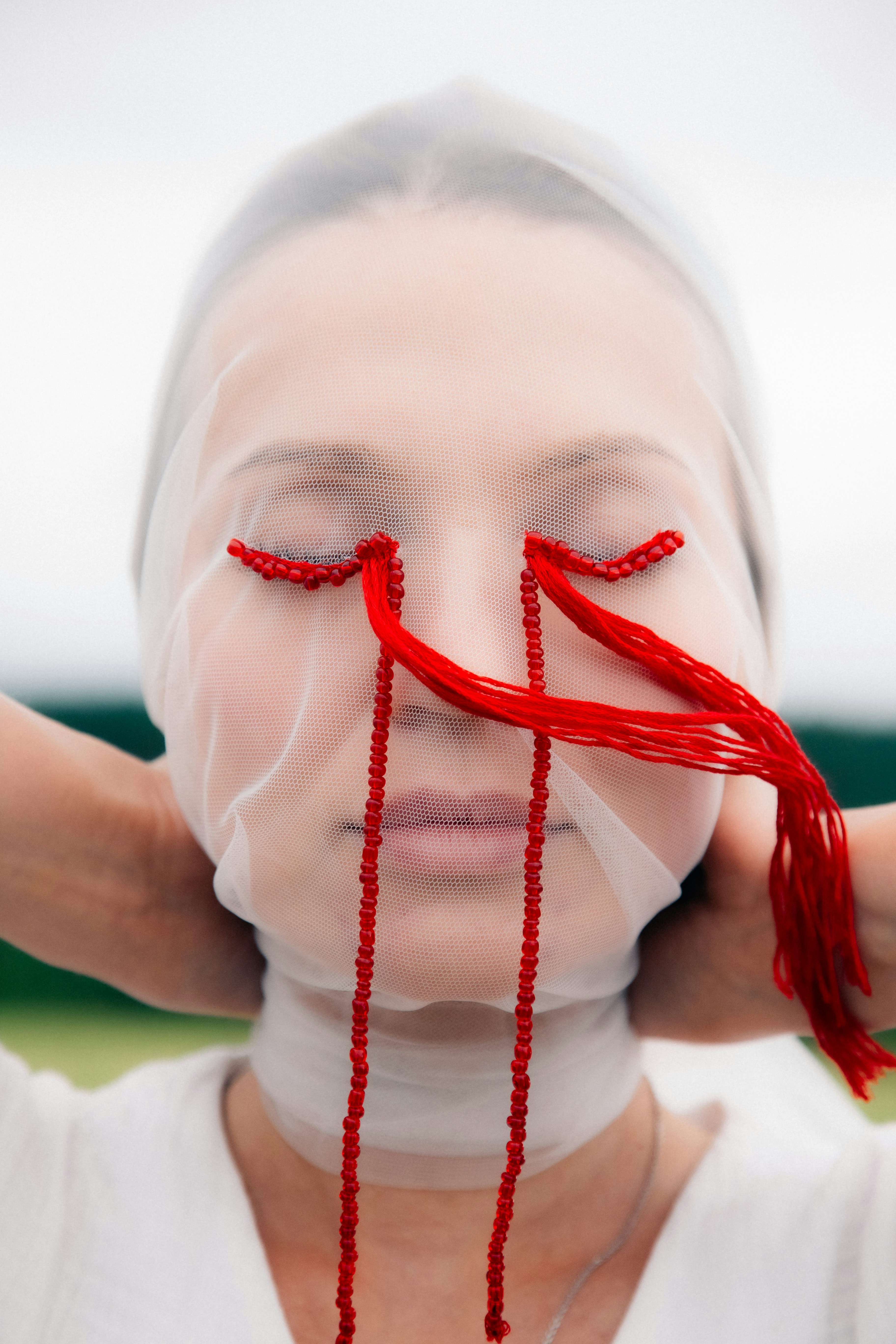 Face veiled in sheer fabric with red beads