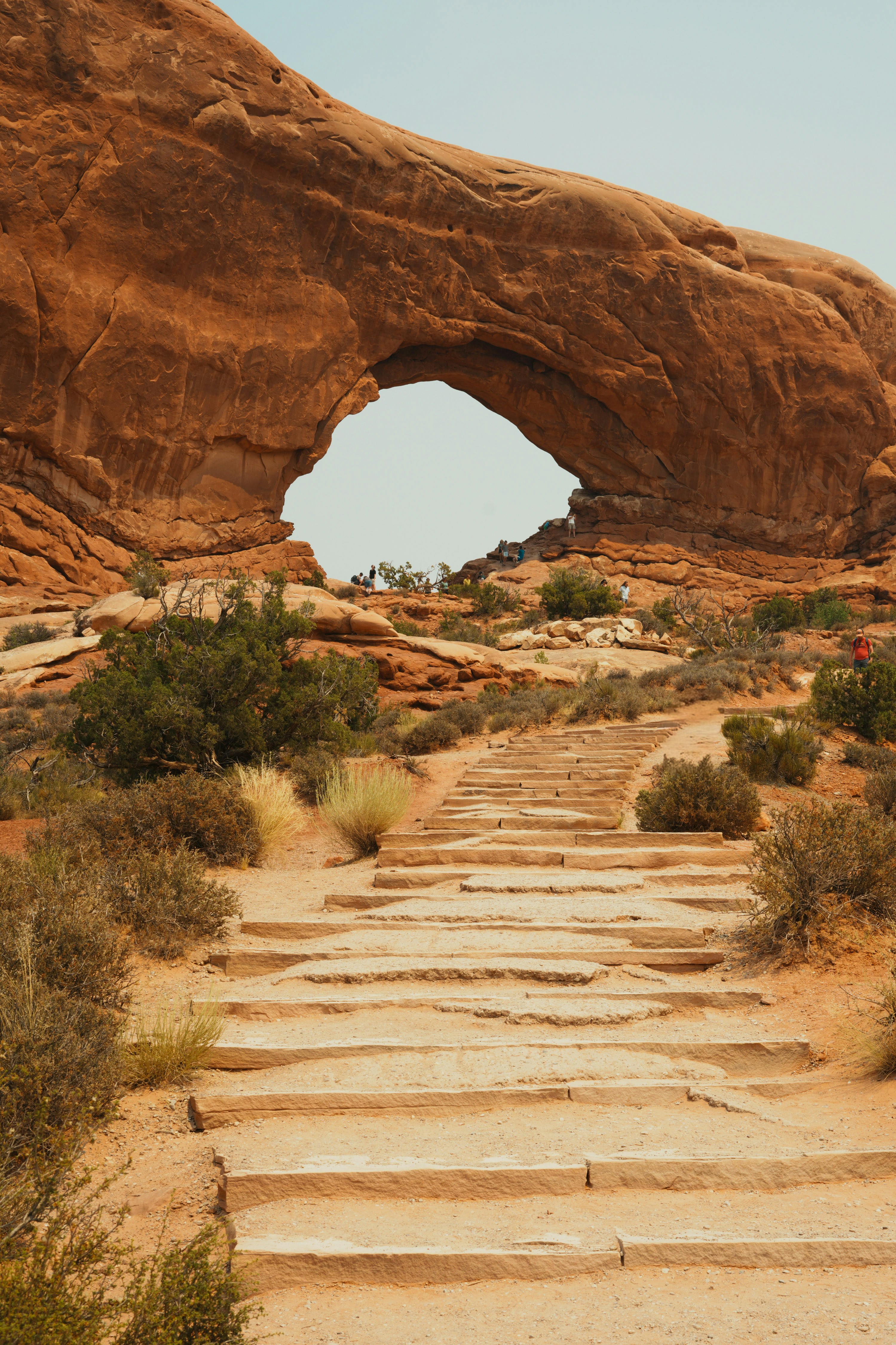 A natural stone arch frames the sky above desert steps