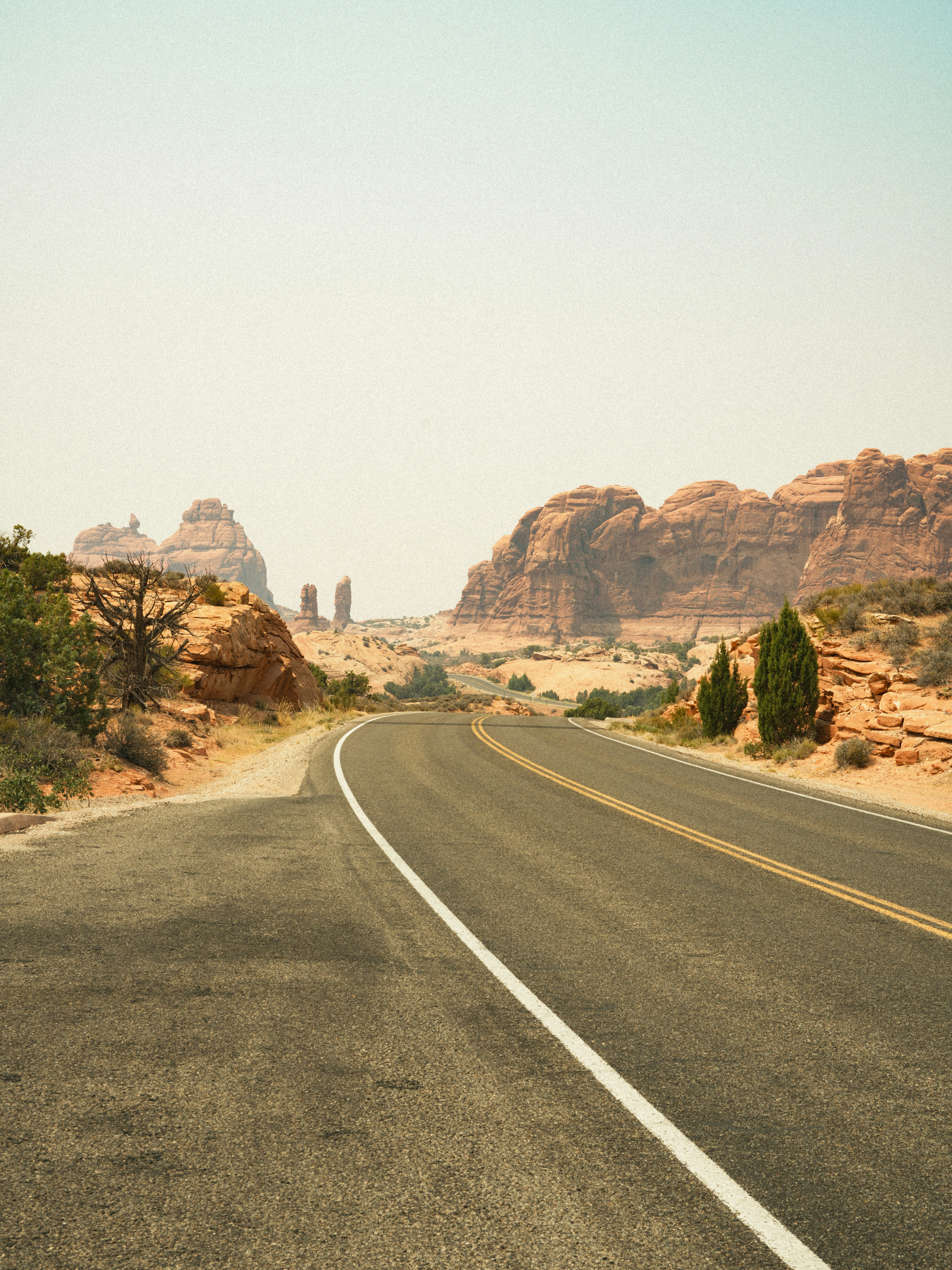 A winding desert road leads through rocky formations