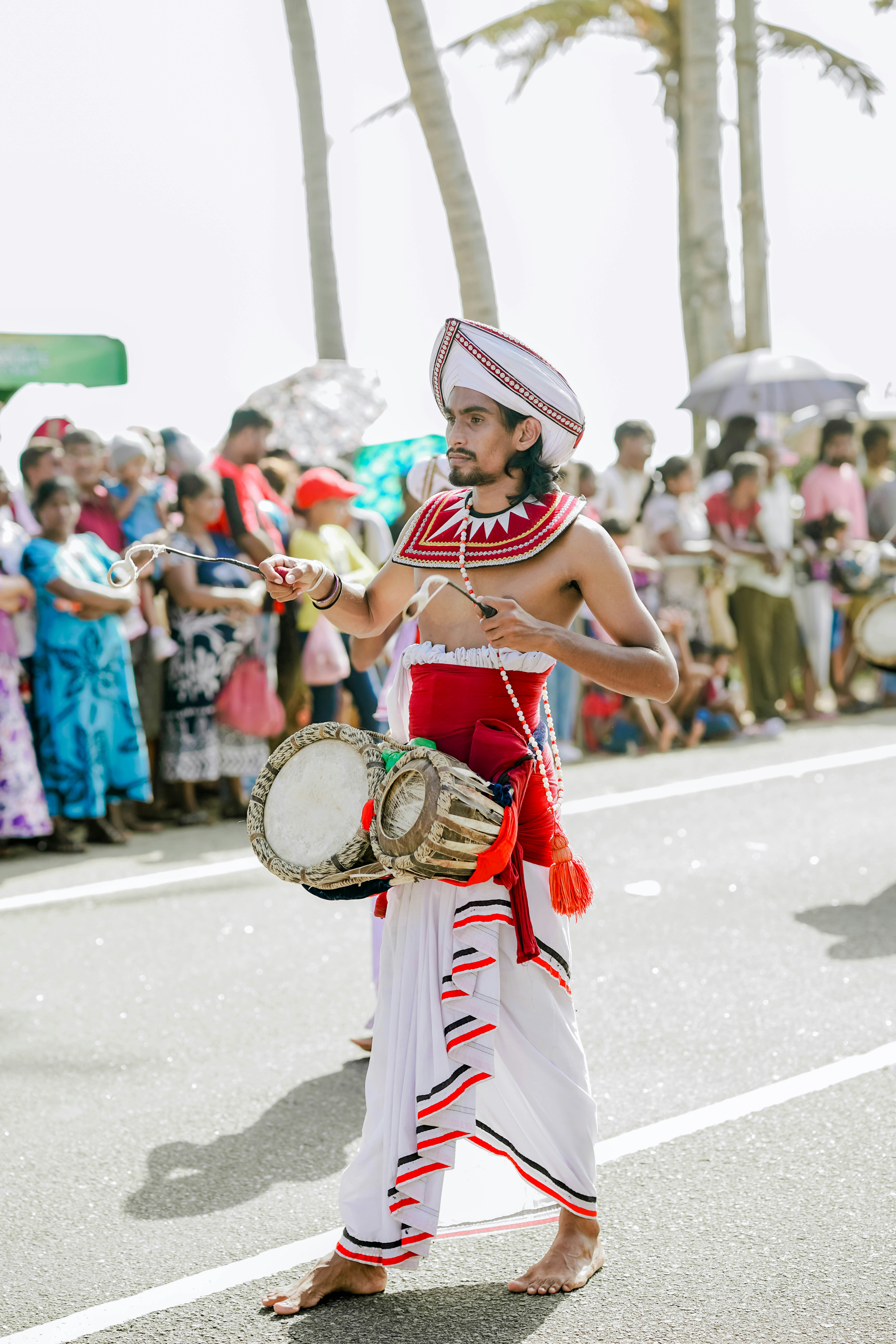 Sri lankan man plays traditional drums during a cultural parade.