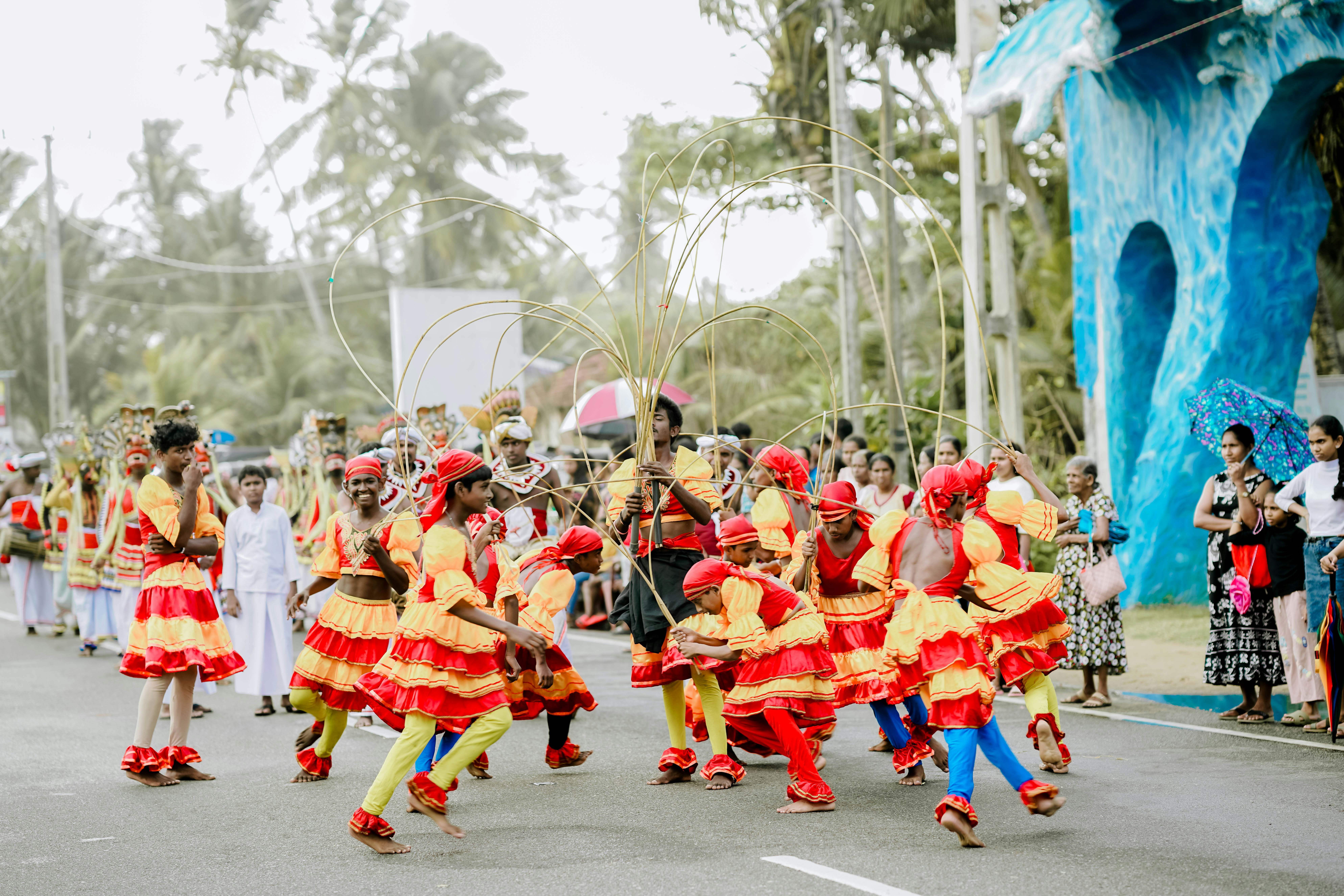Performers in yellow and red costumes parade down a street.