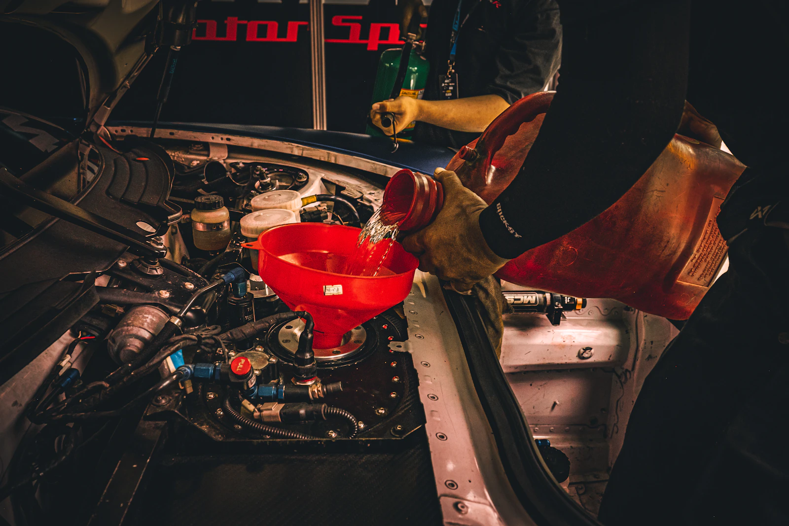 Mecánico vertiendo aceite con embudo rojo en un motor, fotografía de referencia