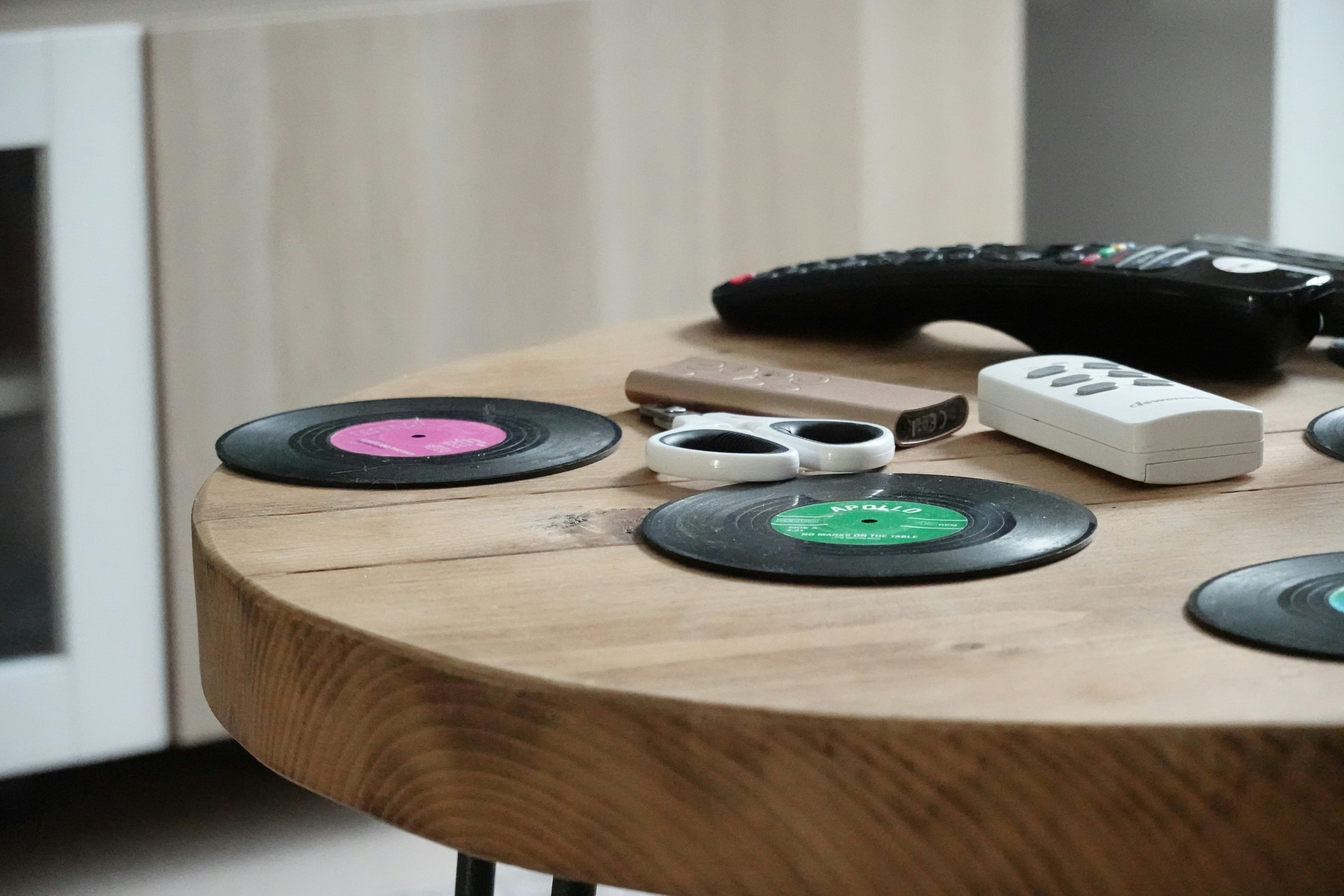 Vinyl record coasters and remotes on a wooden table.