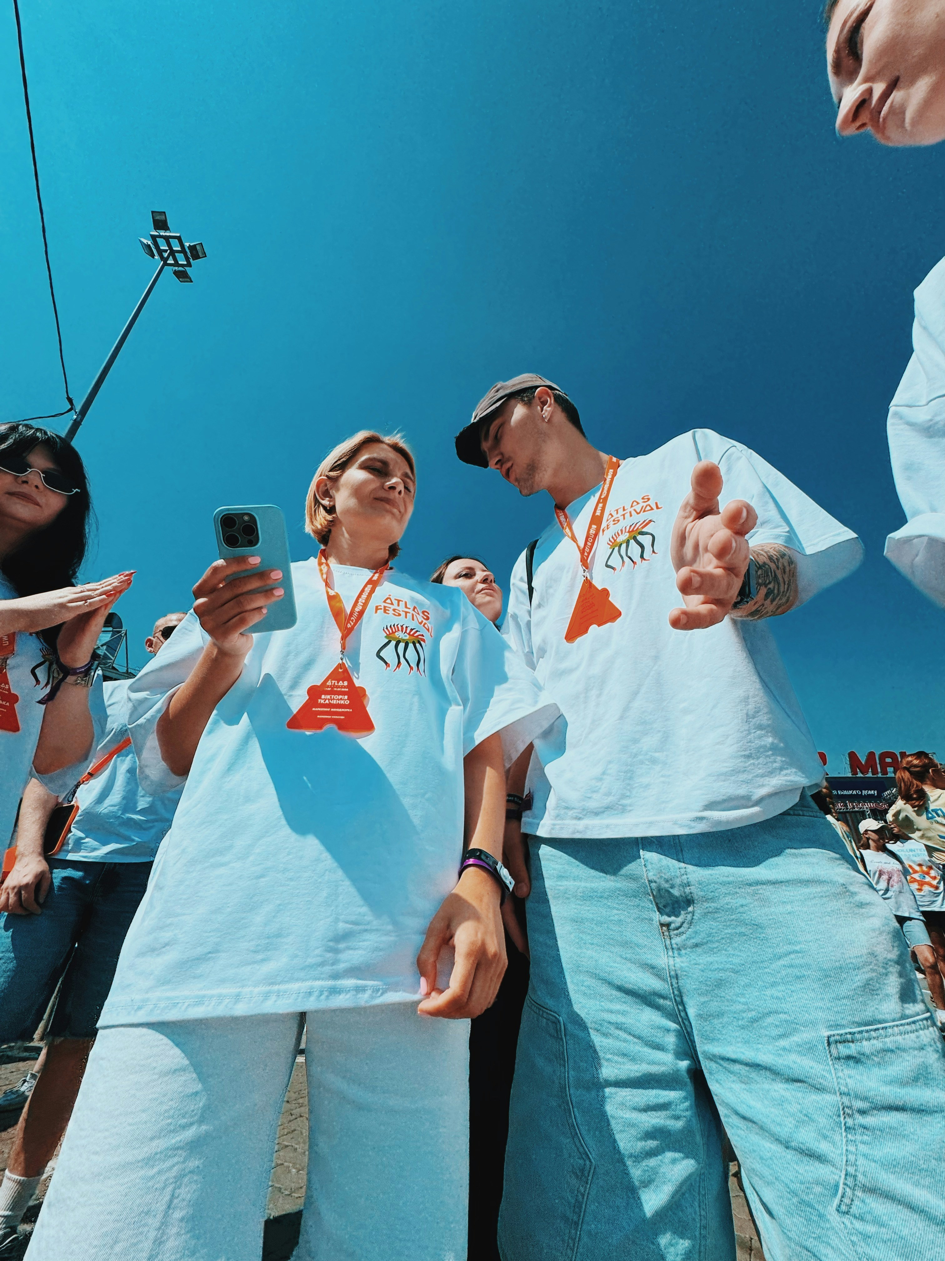 Two young adults in white shirts looking at a phone.