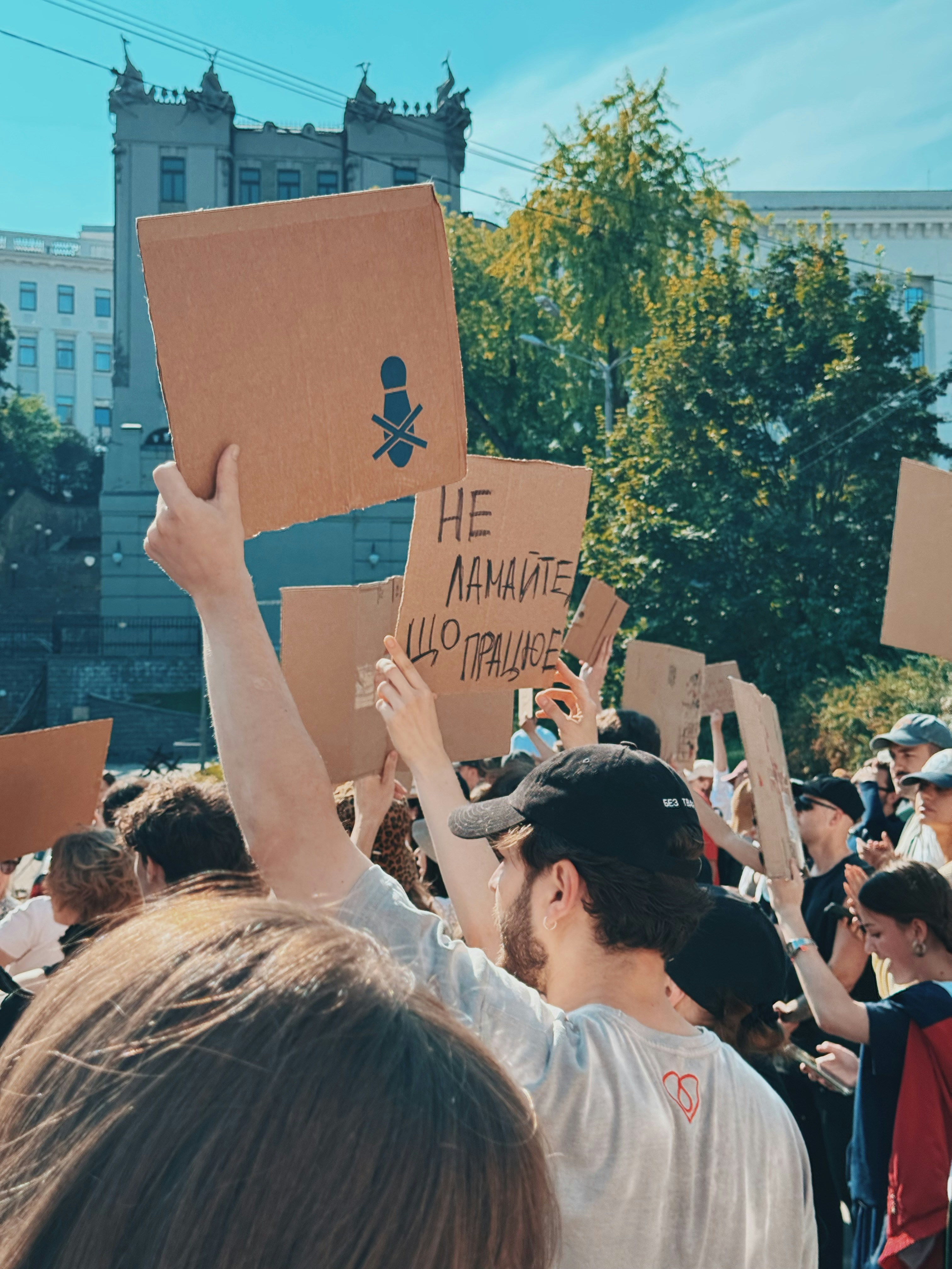 People holding protest signs with a crossed-out microphone symbol.