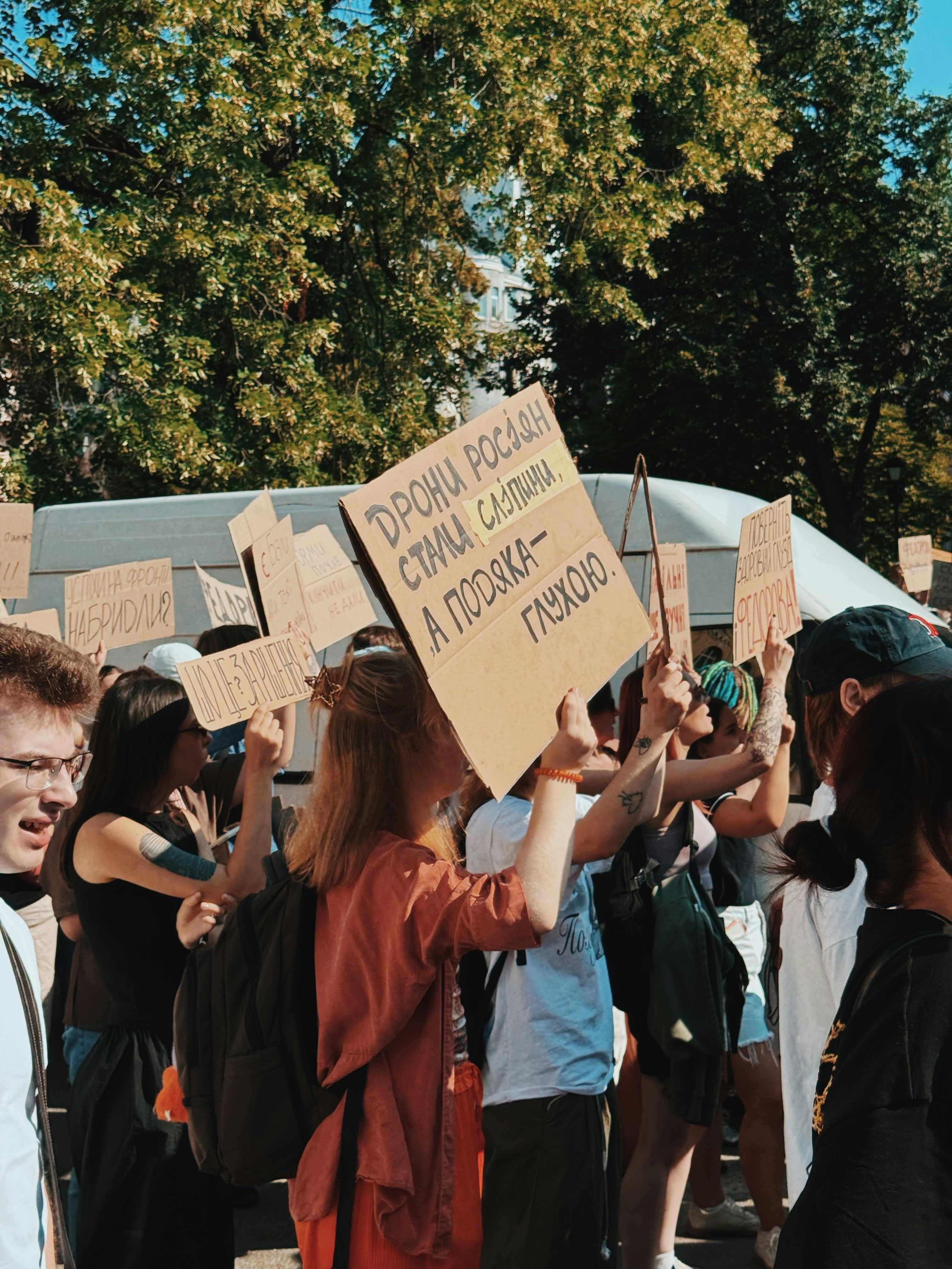 People holding protest signs during an outdoor demonstration.